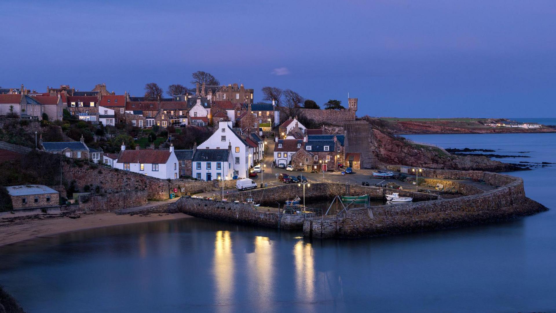 White houses are surrounded by the harbour amd dark sea.