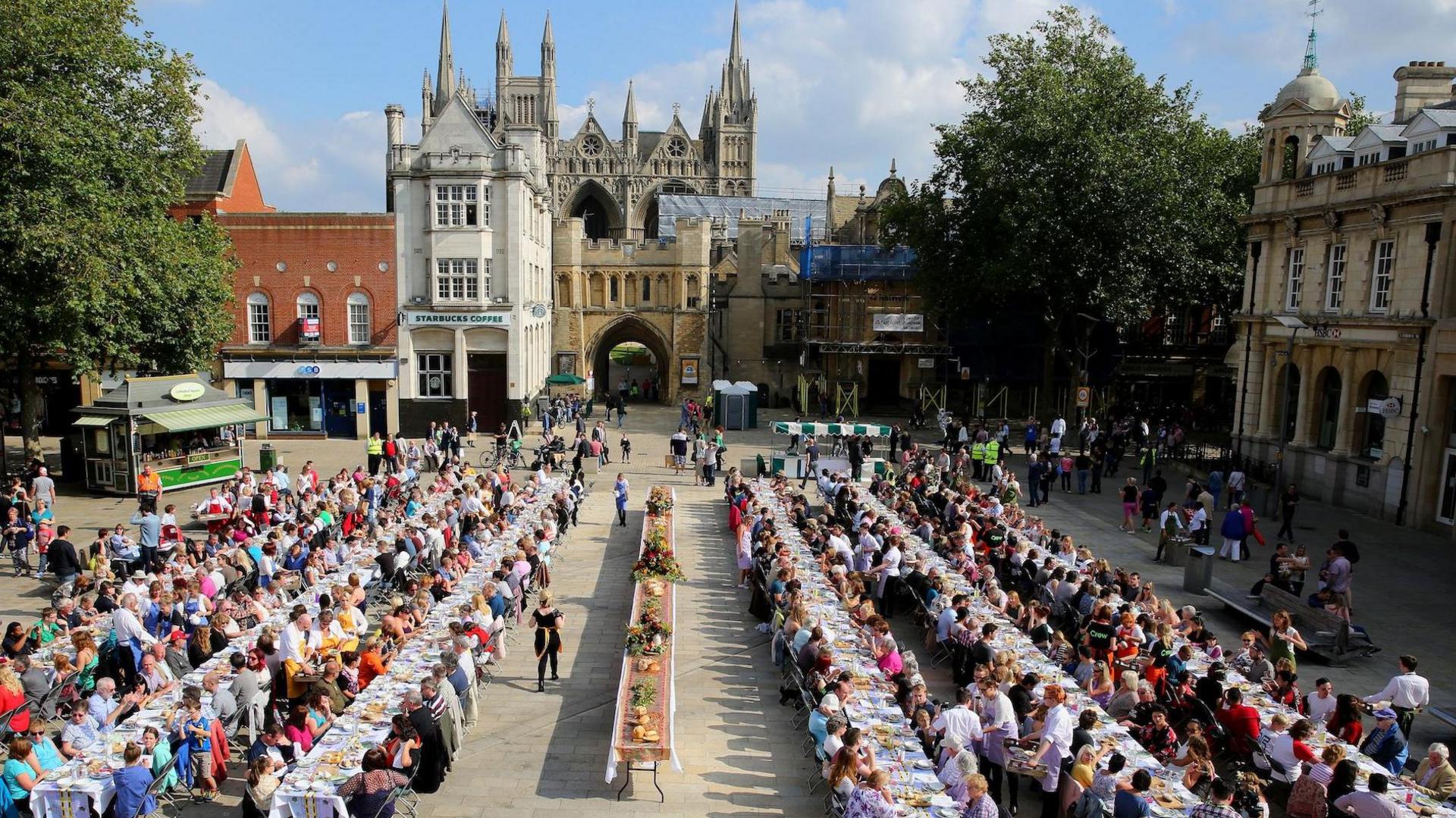 Trestle tables set up in Cathedral Square in Peterborough with hundreds of people eating