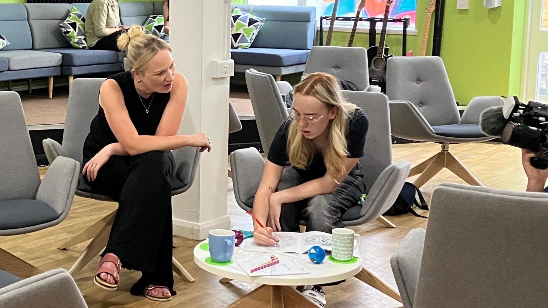 Lois using a colouring book as Inspire staff sit next to her