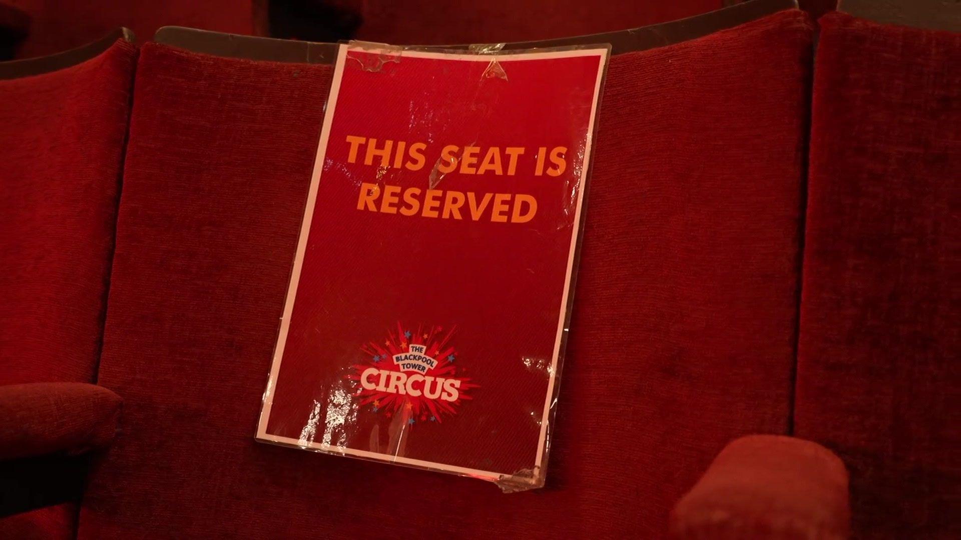 A red velvet circus seat with a red sign attached by Blackpool Tower Circus which reads: 'This seat is reserved.'