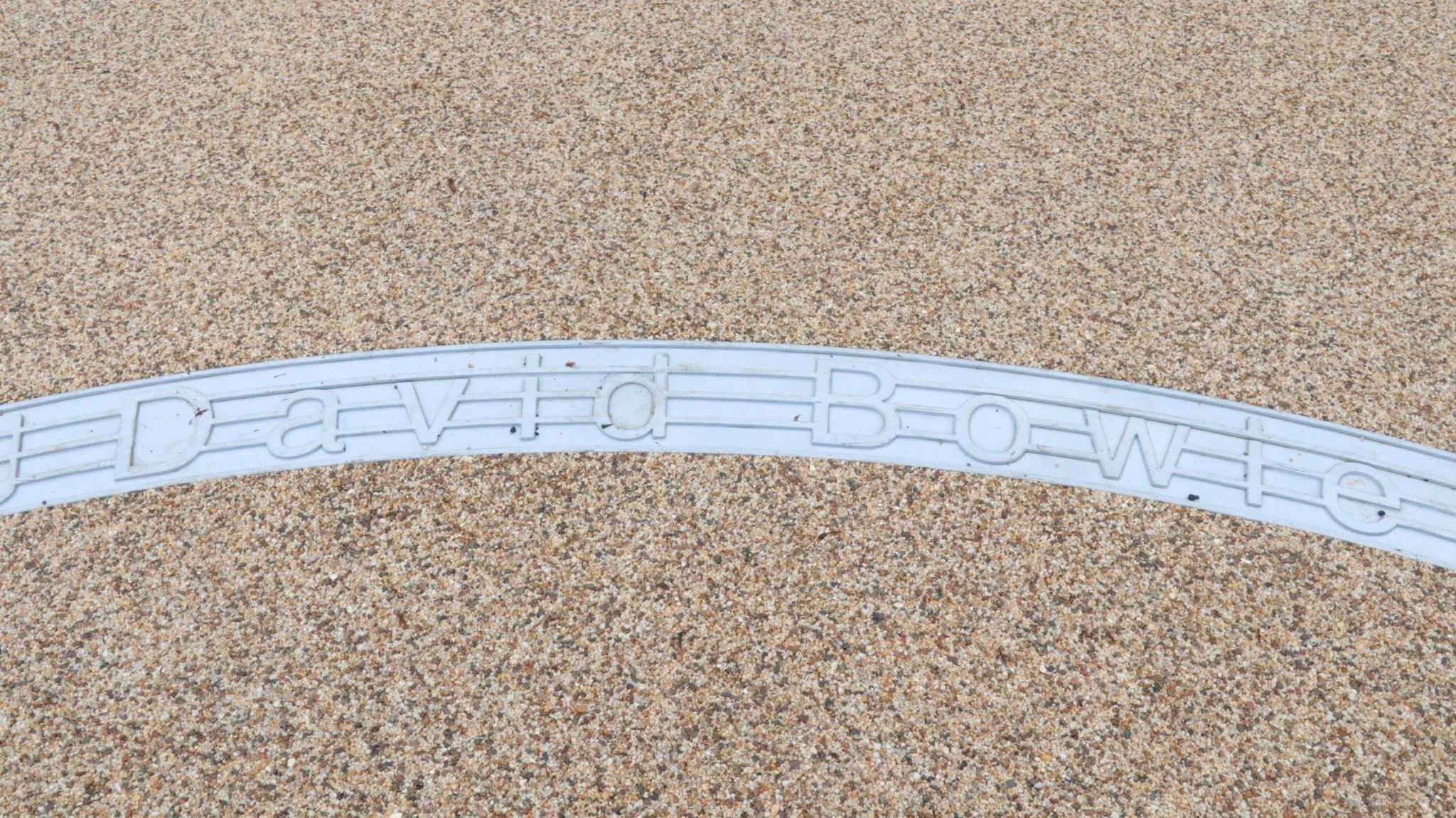 A metal inlay in the ground with the name "David Bowie" written on it