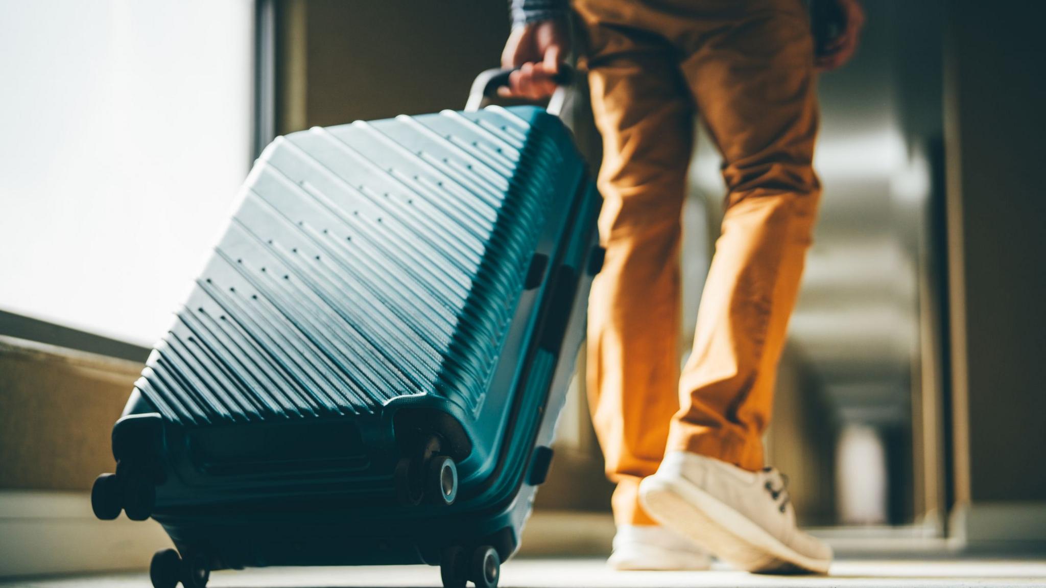 A person pulls a suitcase along a corridor.