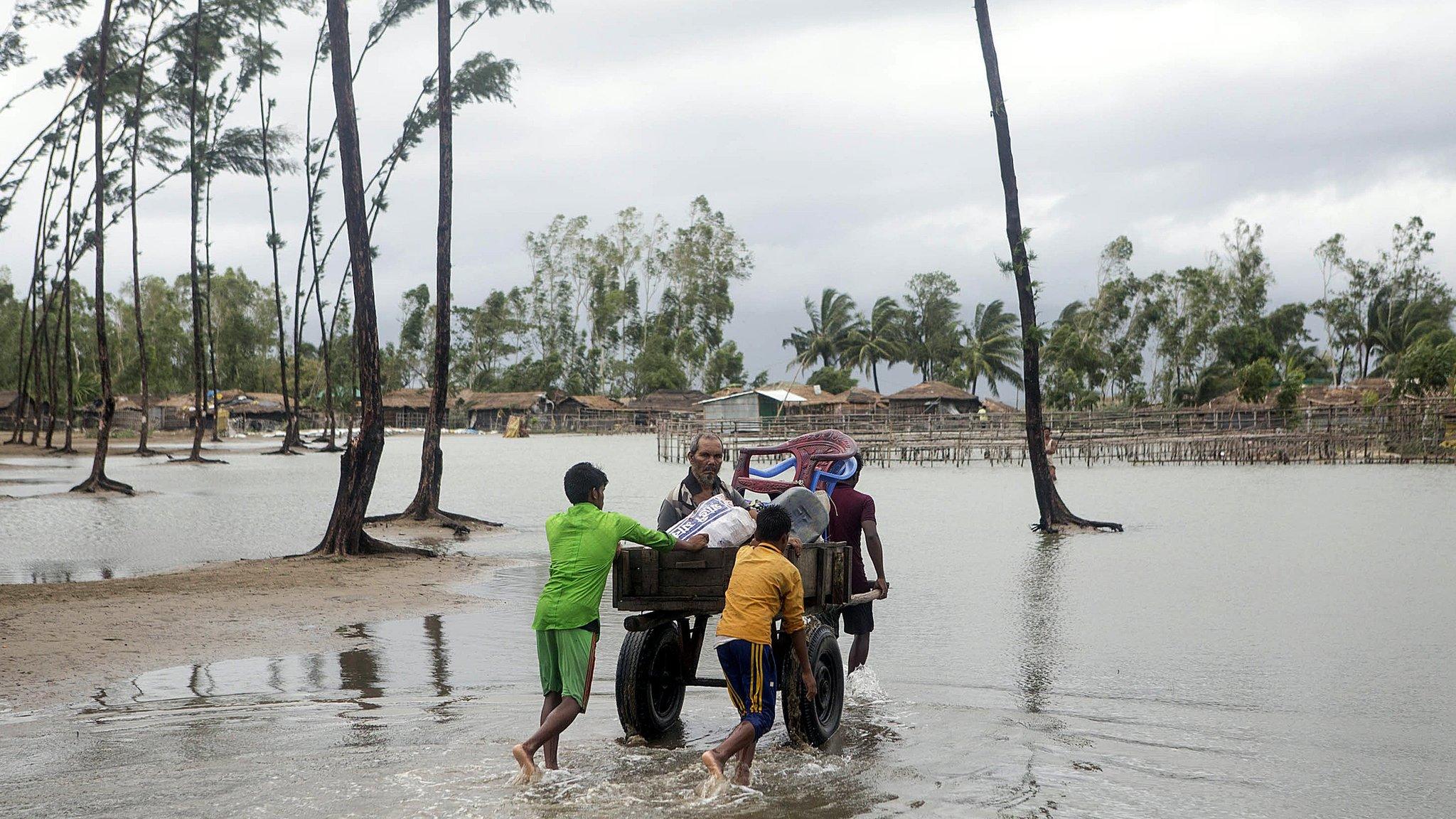 Bangladeshi people walk with their belongings towards a safer area near the coastal line at the Cox's Bazar district in the Chittagong, in Bangladesh, 30 May 2017