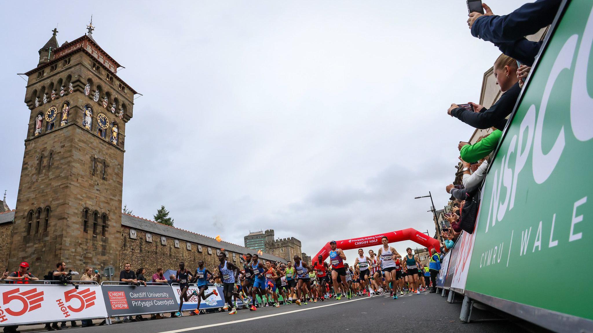 Runners in the marathon in the distance while running in front of Cardiff Castle