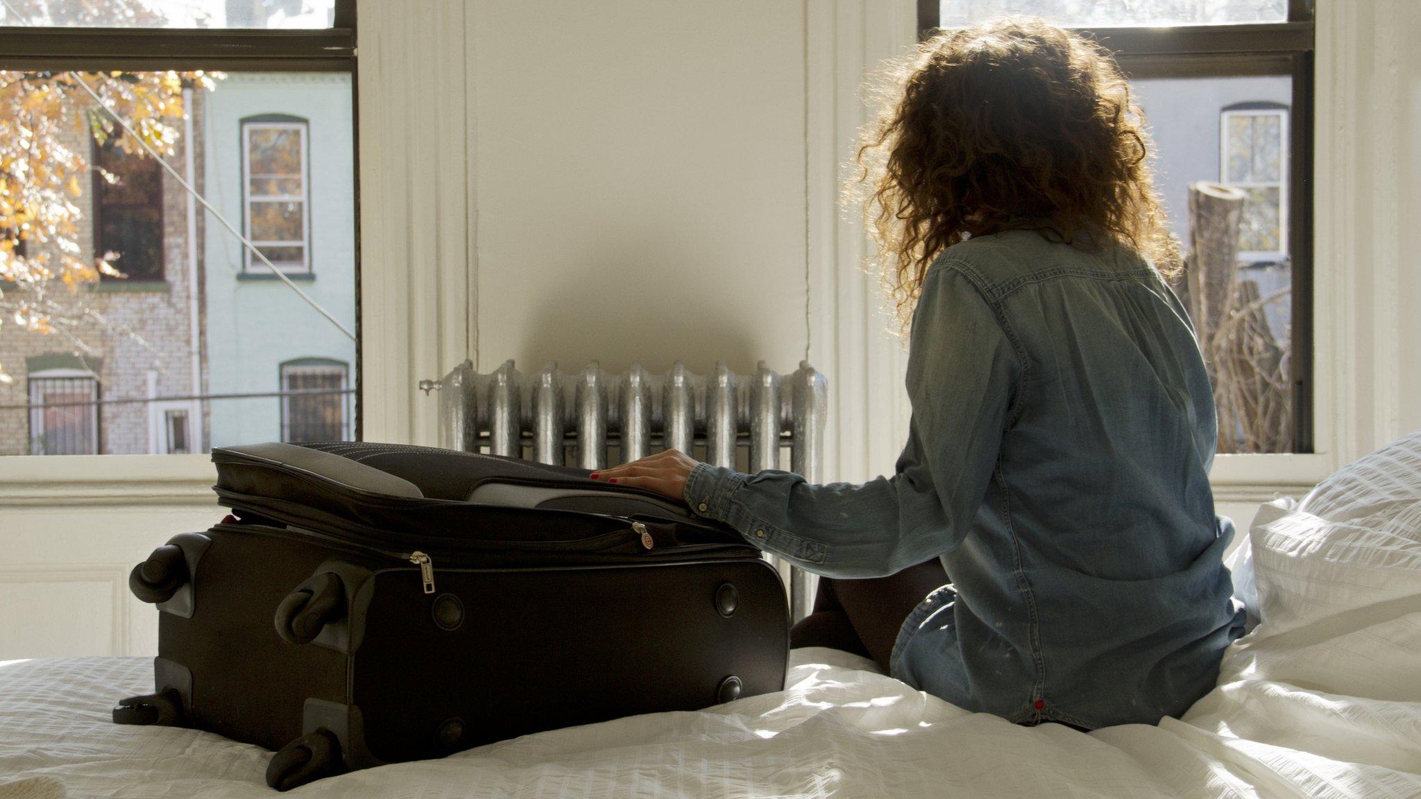 Female traveller sat on an Airbnb bed.