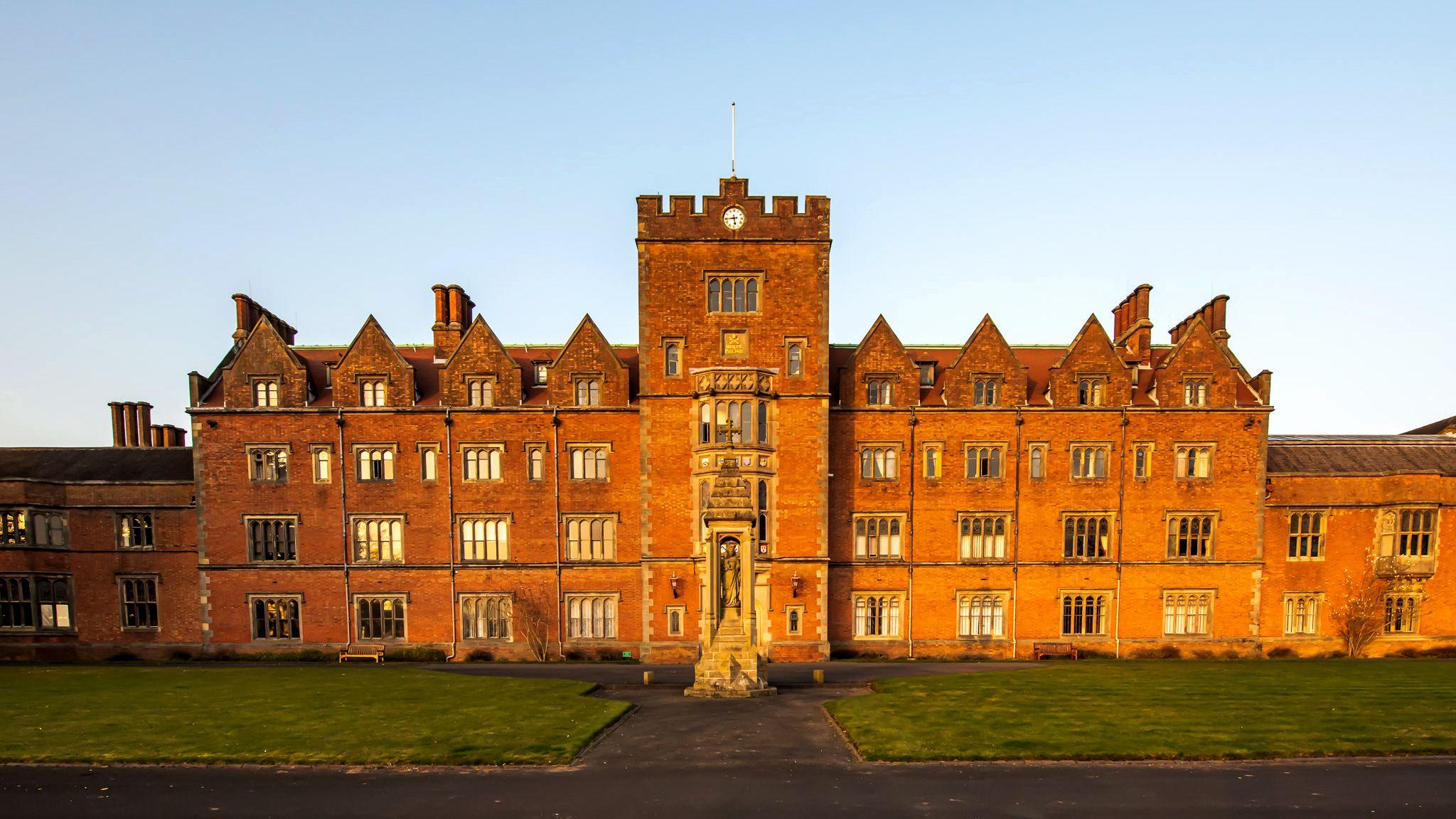 A red brick 19th Century college showing the main entrance and four storeys