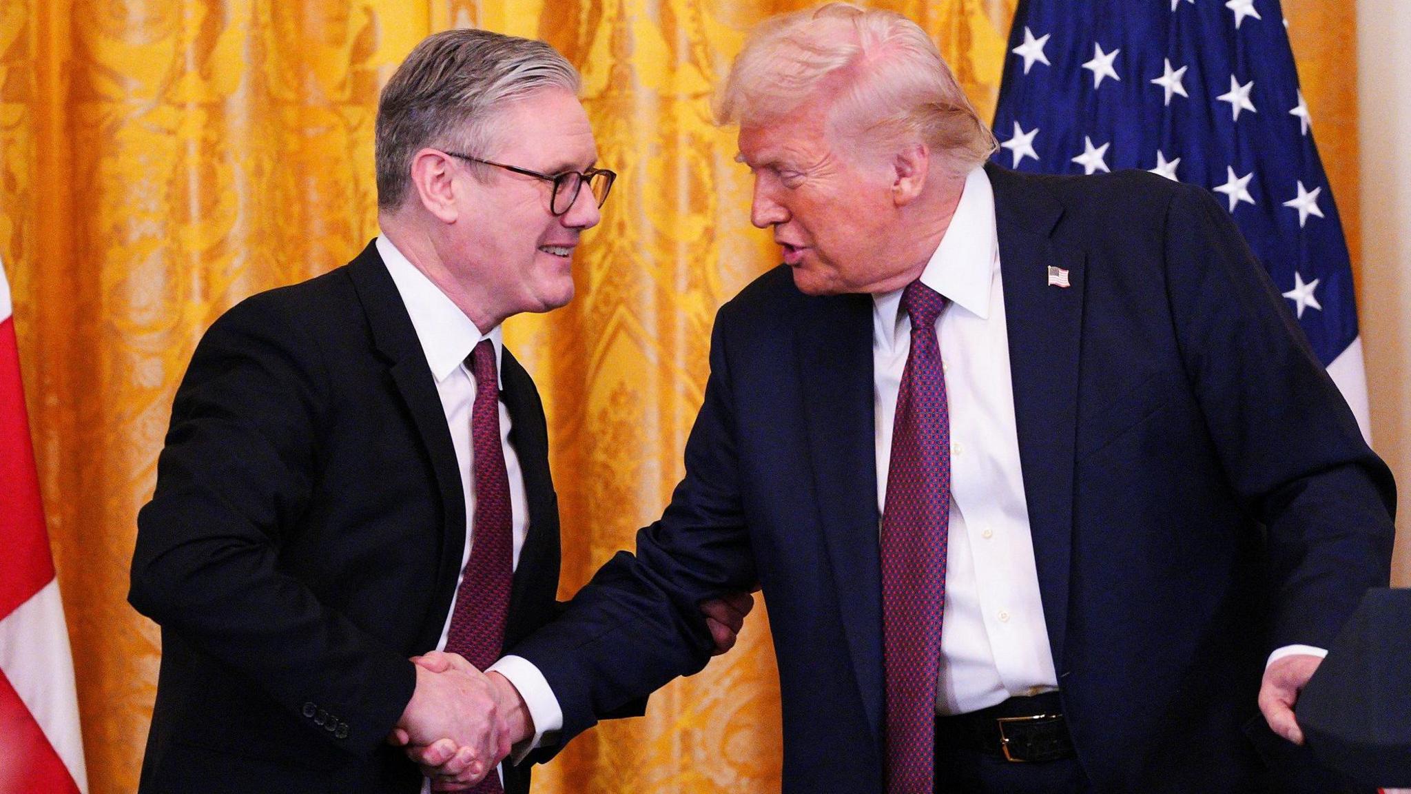 Sir Keir Starmer and Donald Trump shake hands in front of a yellow curtain and US flag ahead of their news conference