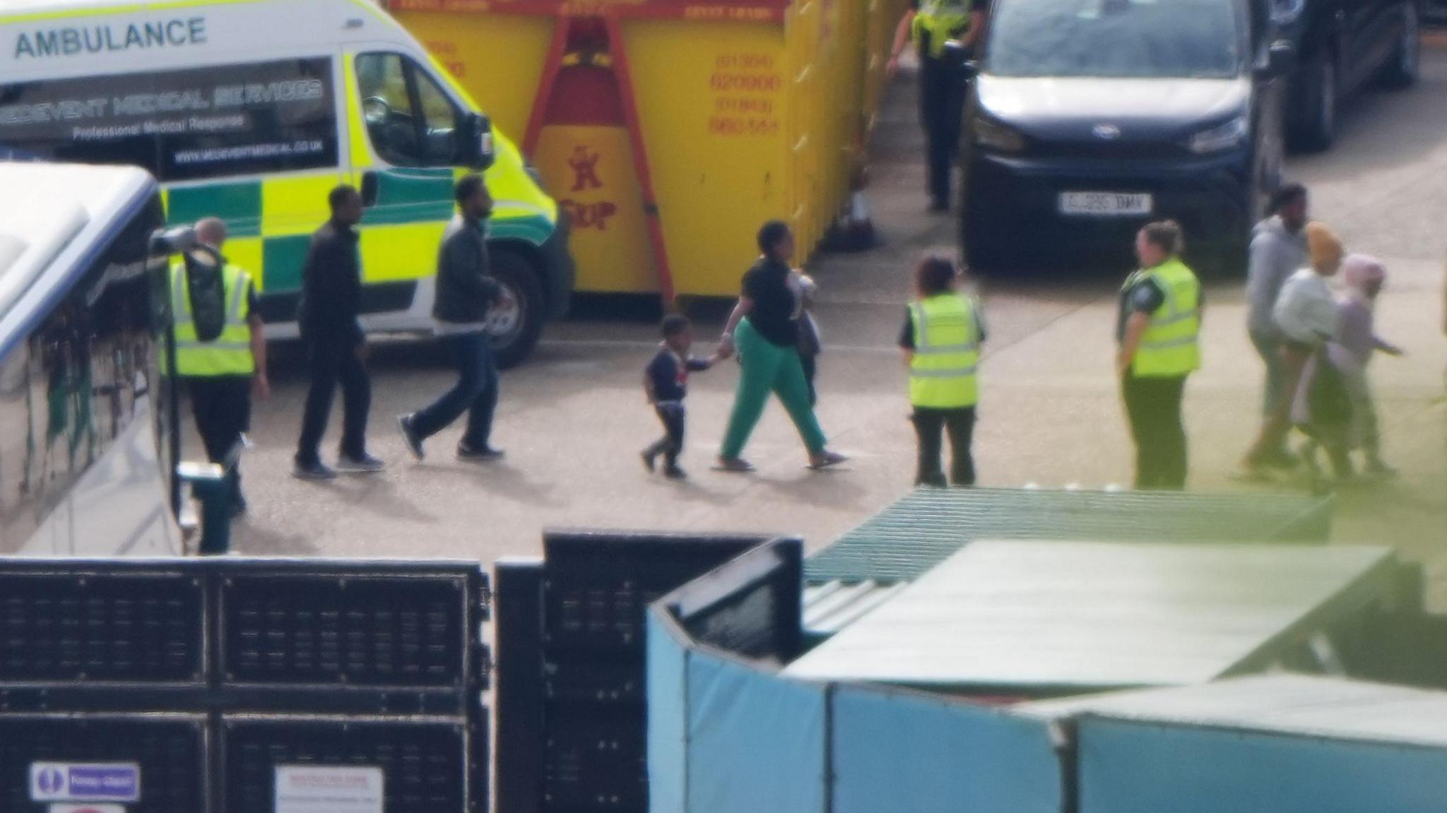 A small group of migrants - including children - being led by immigration officials on a tarmac at the Port of Dover on Saturday