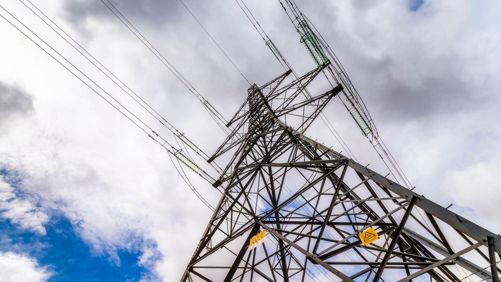 A close up of the top of an electricity pylon taken from below