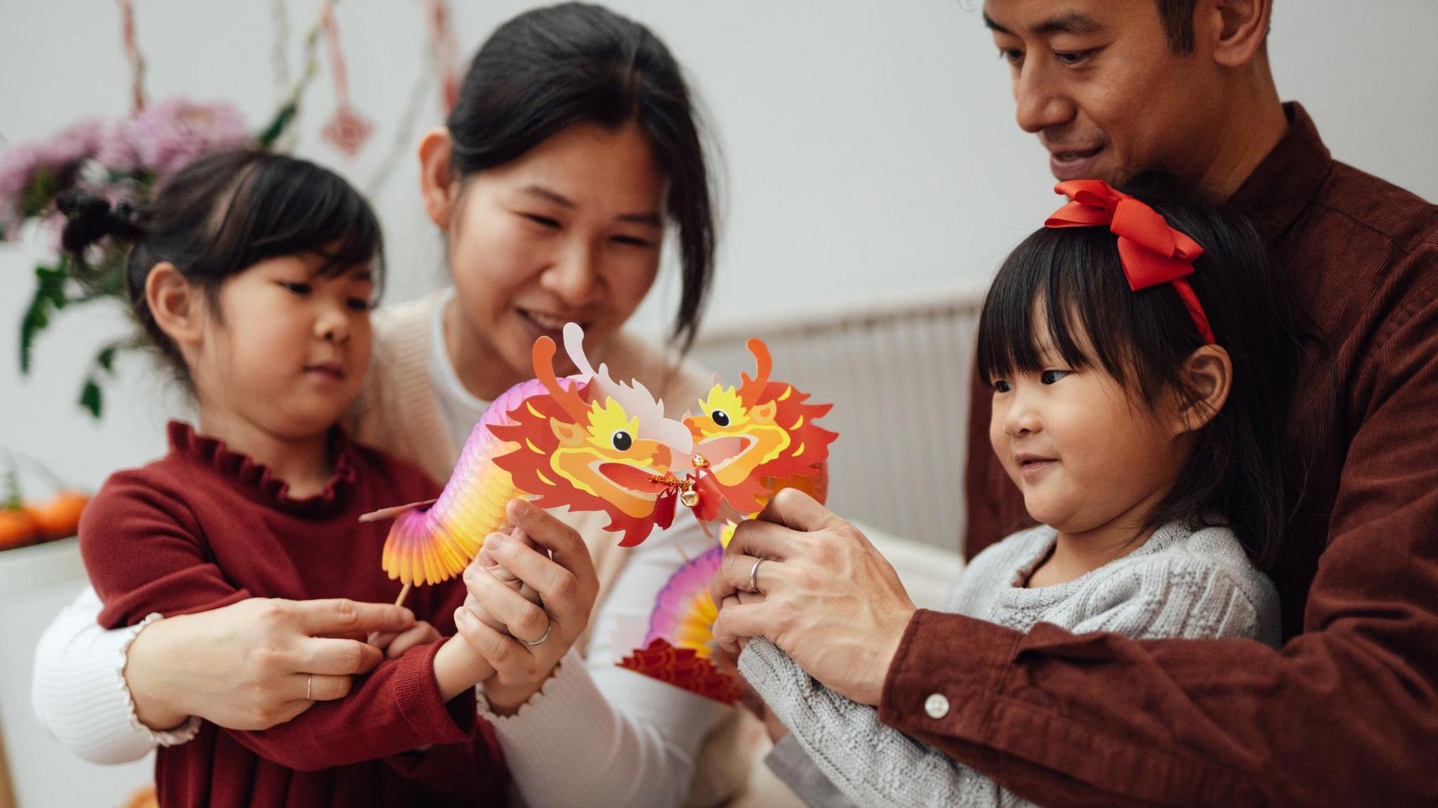 children playing with paper dragons with their parents