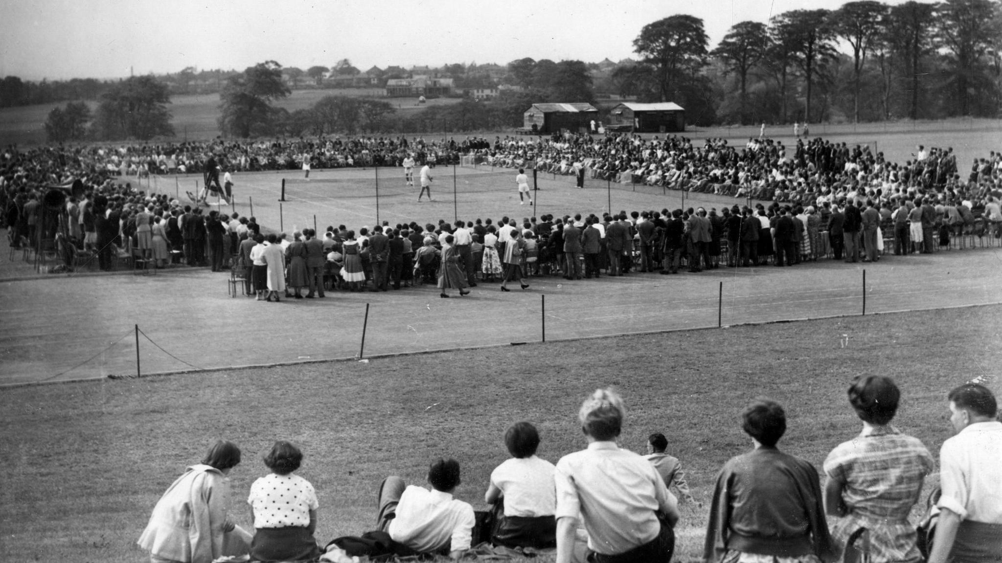 The track being used for a tennis match in the 1950s