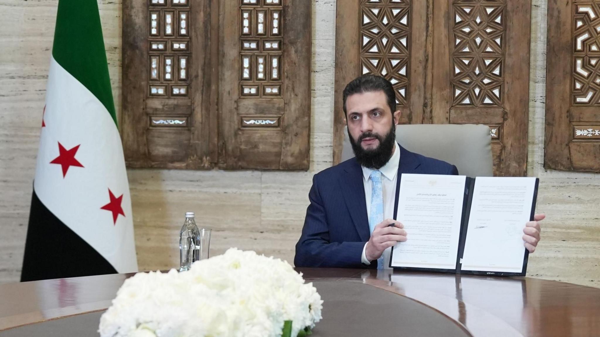 Presidenti sirian Ahmed al-Sharaa mban në dorë një marrëveshje prej 14 pikash me Forcat Demokratike Siriane (SDF), e cila i jep qeverisë kontrollin mbi Sirinë verilindore të drejtuar nga kurdët, në Damask, Siri (18 janar 2026)