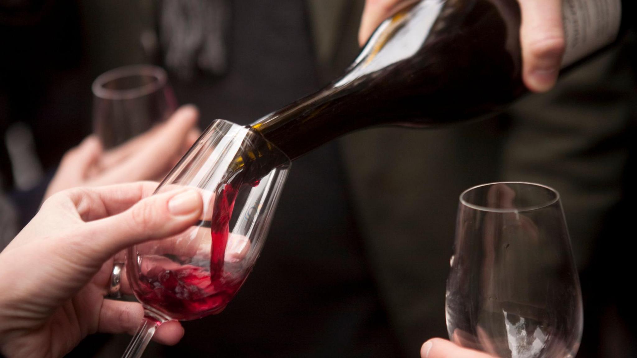 A bottle of Beaujolais Nouveau red wine being poured into a glass