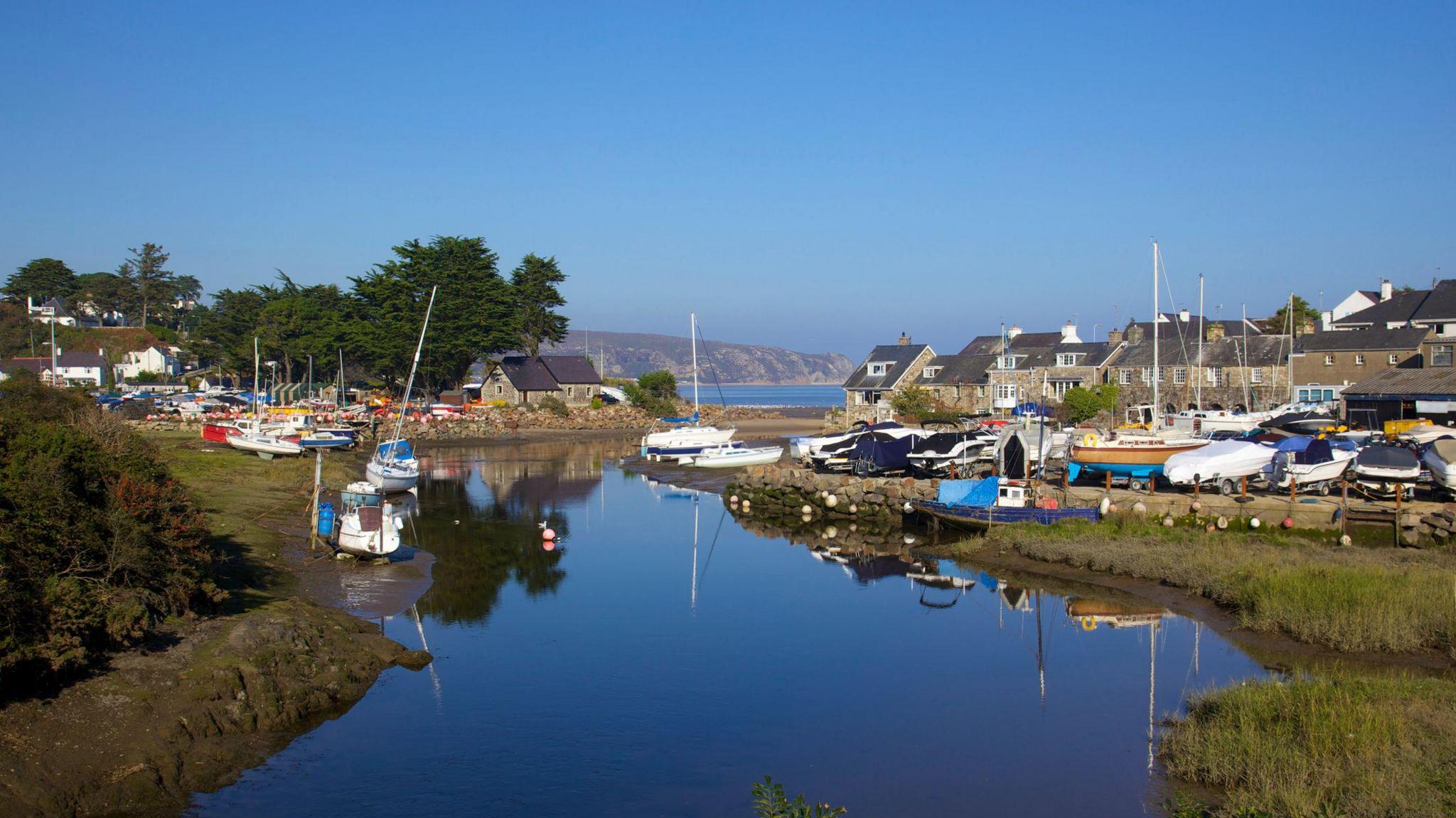 Llun o afon yn llifo allan i'r môr. I'r ddwy ochr o'r afon mae yna longau a thai.