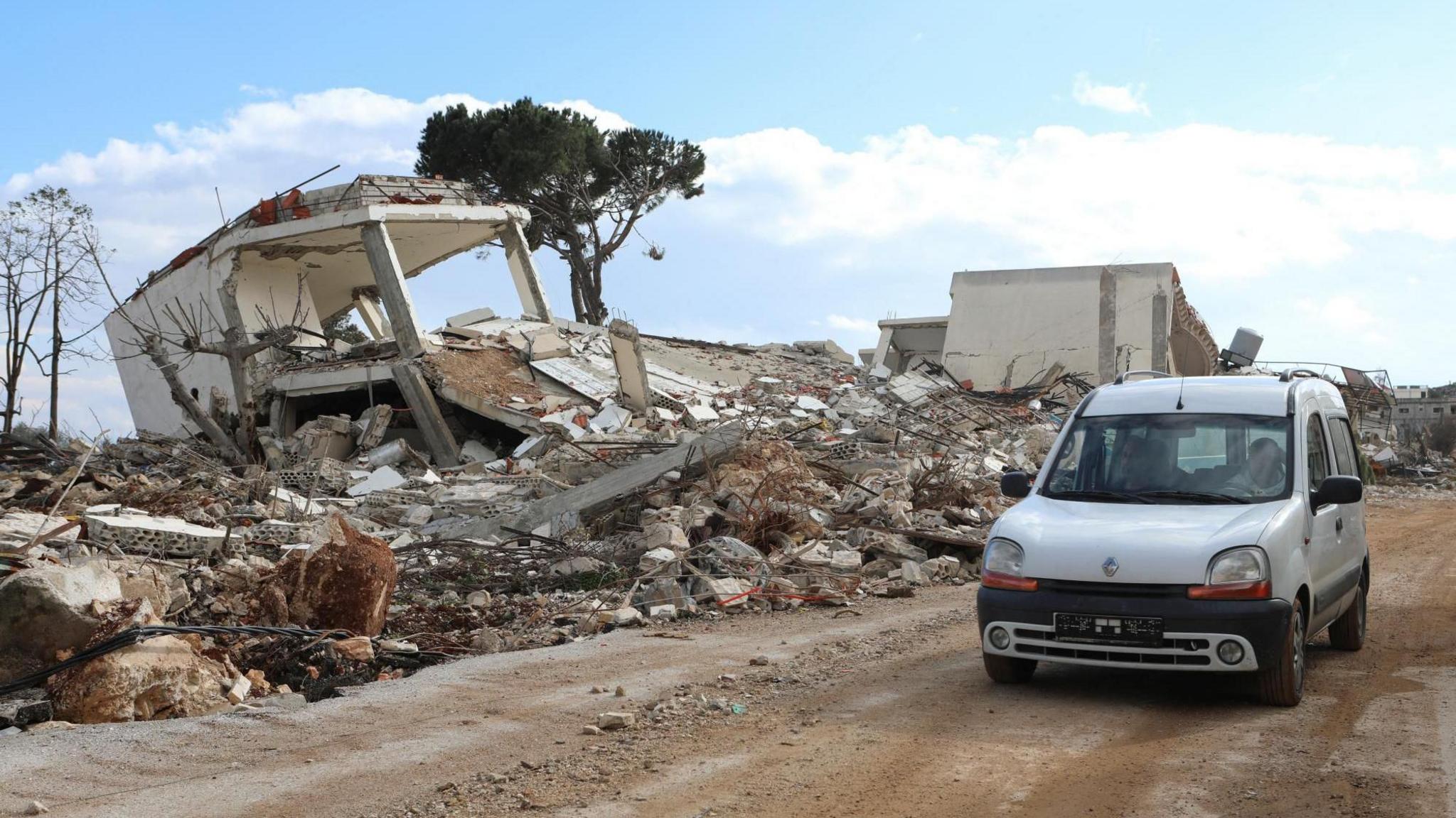 People drive past a damaged site in the southern Lebanese village of Khiam, near the border with Israel
