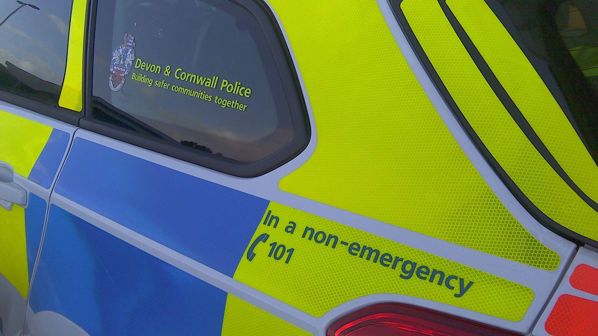 The blue and fluorescent yellow colouring on a Devon and Cornwall Police car.
A notice on the car also tells people to call 101 in a non-emergency.