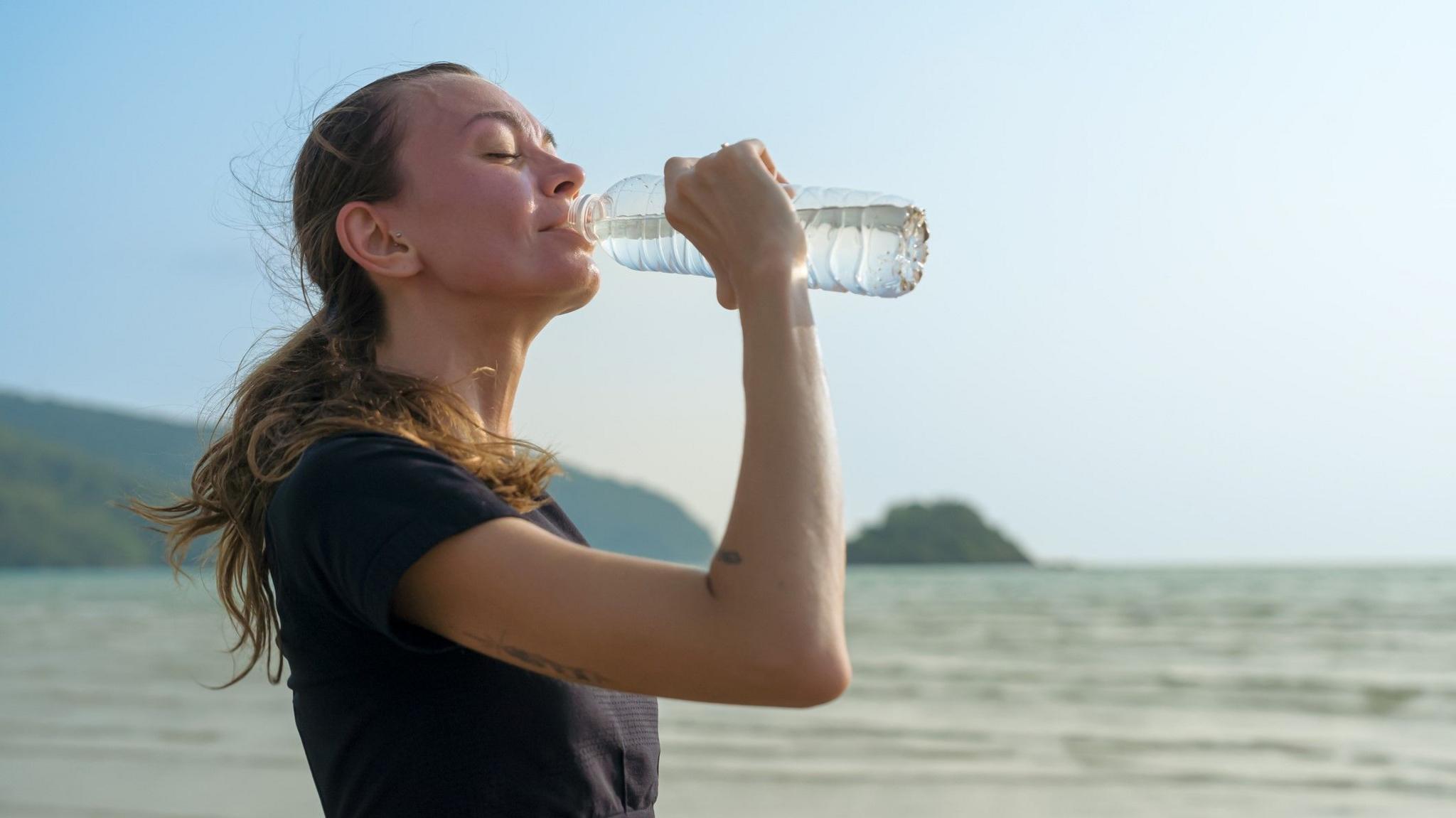 A woman drinks water in a stock image