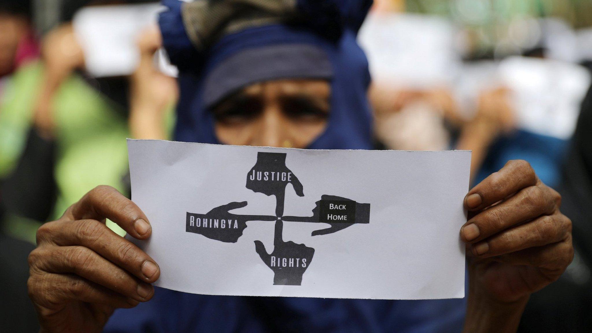 A Rohingya protester holds a placard