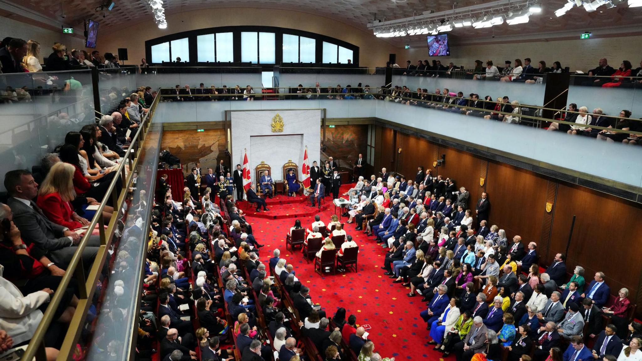People gathered in the building the Senate is currently using, which was once Ottawa's main rail station. It has a bright red carpet.