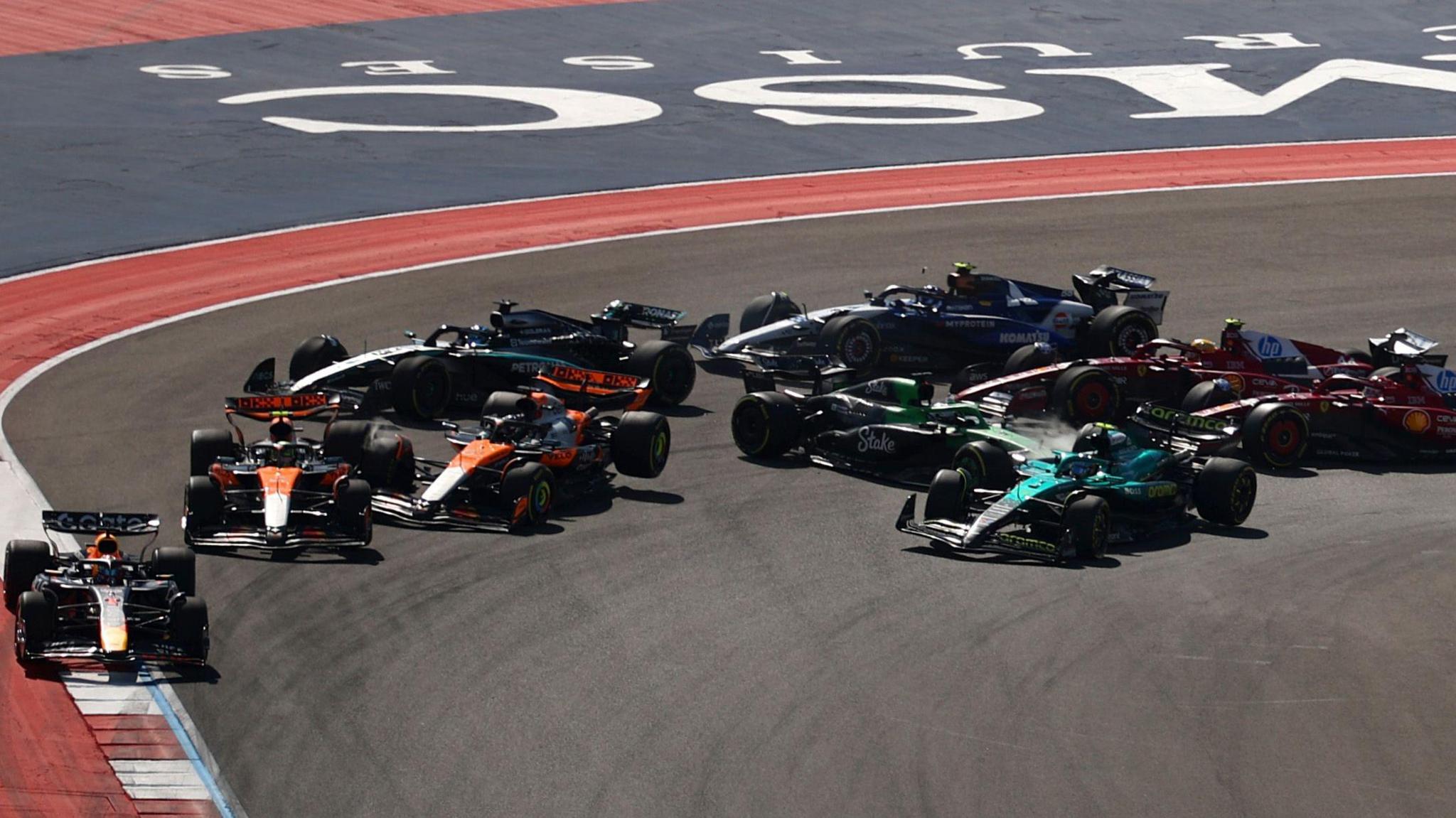 The cars sweep around the first corner of the US Grand Prix sprint race as the McLarens of Lando Norris and Oscar Piastri collide