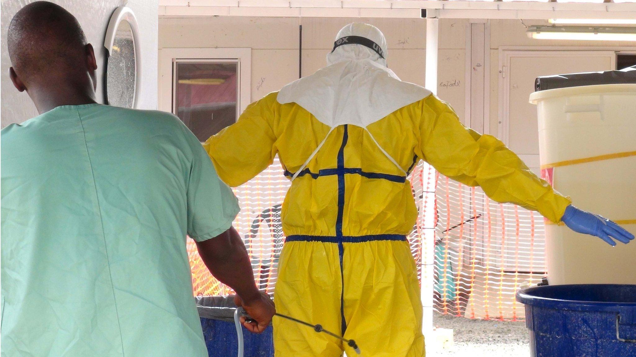 A health worker gets sprayed with disinfectant in an Ebola virus treatment center in Conakry