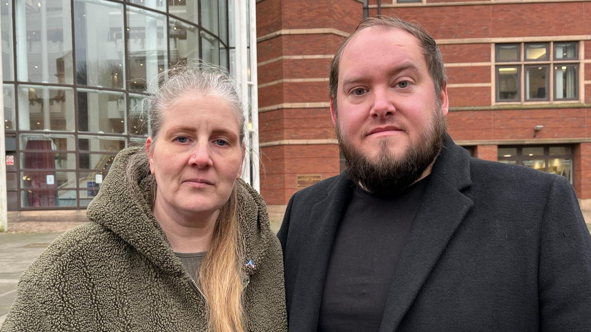 Parents of Wynter Andrew, Sarah and Gary. Sarah is wearing a khaki, fluffy hooded jacket with her hair tied in a pony. Gary is wearing a black wool coat. 