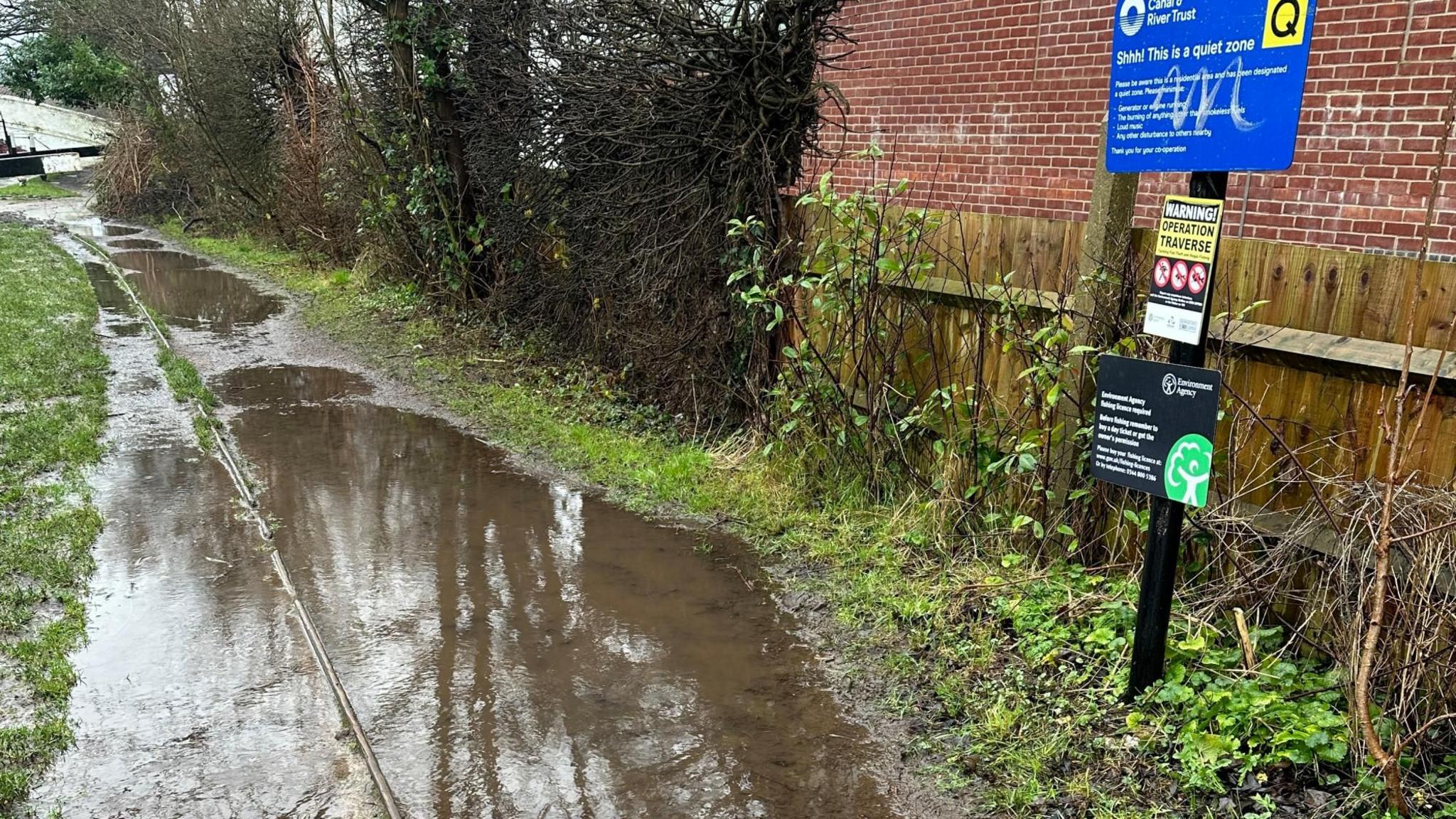 Large brown puddles fill the walking space on a tow path.