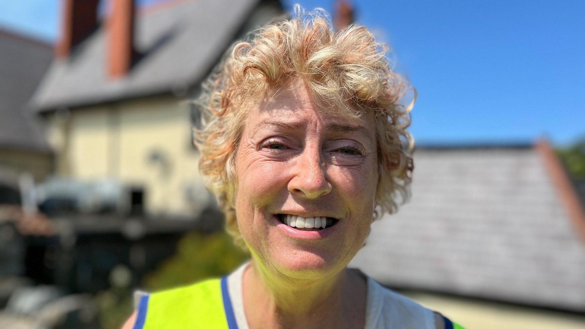 Rita smiling wearing a neon greenish hullo vis jacket.