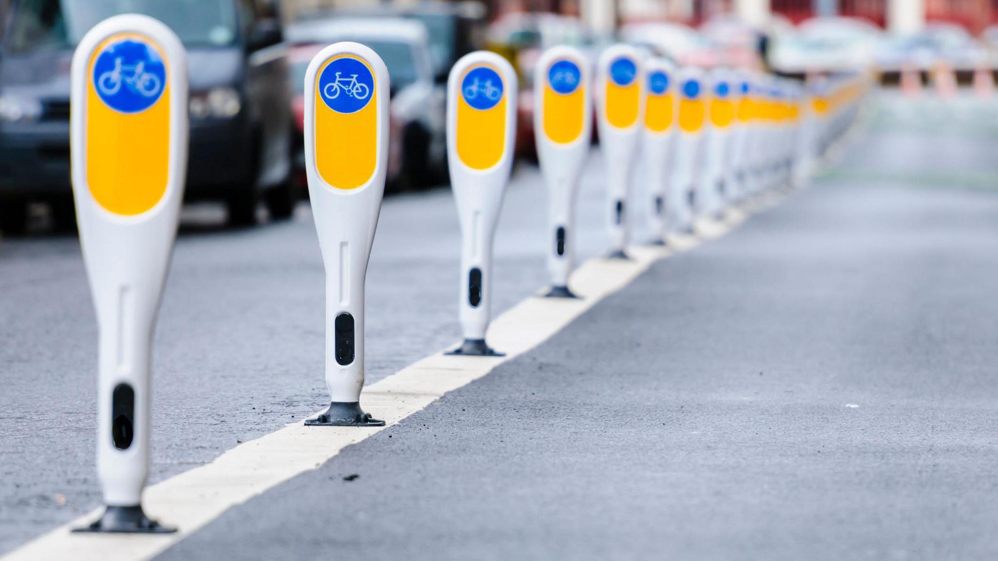 Row of bollards separating a cycle lane from motor vehicles.