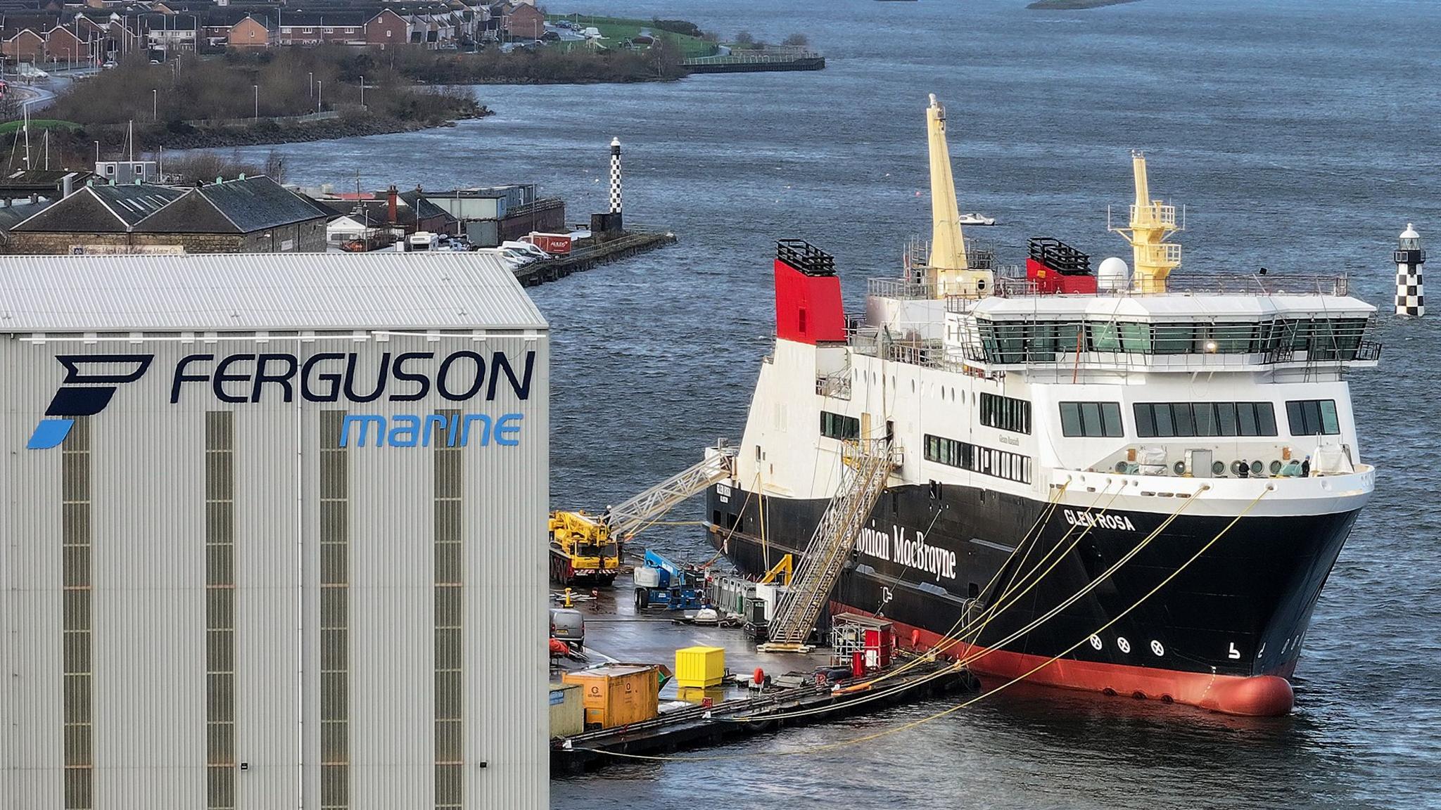 The Glen Rosa ferry under construction at Ferguson's shipyard. To its left there is a large grey building with the words Ferguson Marine on the side.