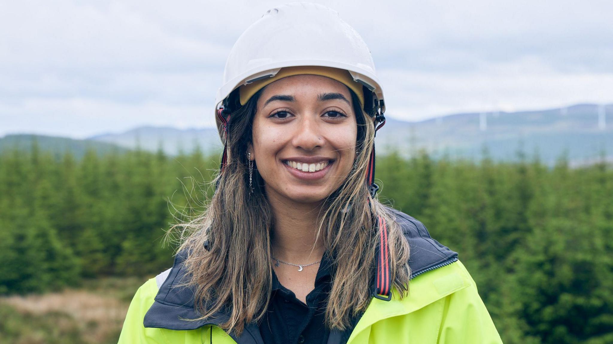 Eishar Bassan with long brown hair wearing a hard hat and hi-vis jacket