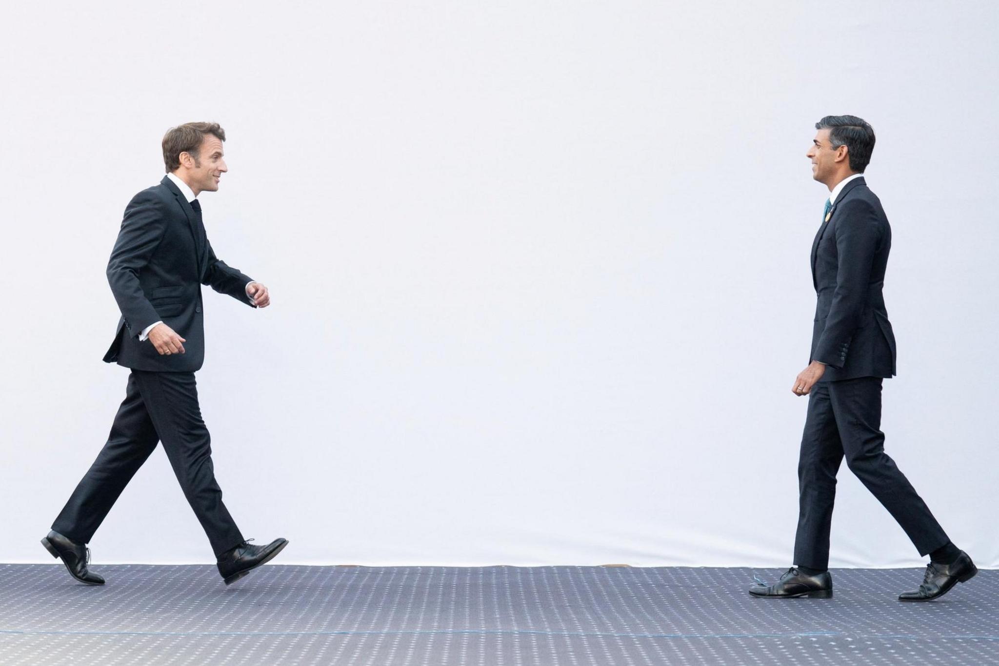 French President Emmanuel Macron strides towards Prime Minister Rishi Sunak ahead of their meeting