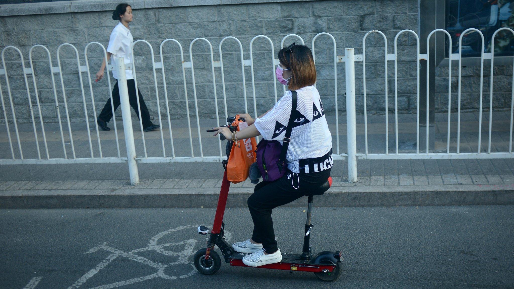 A Chinese woman drives an electric scooter along a street in Beijing