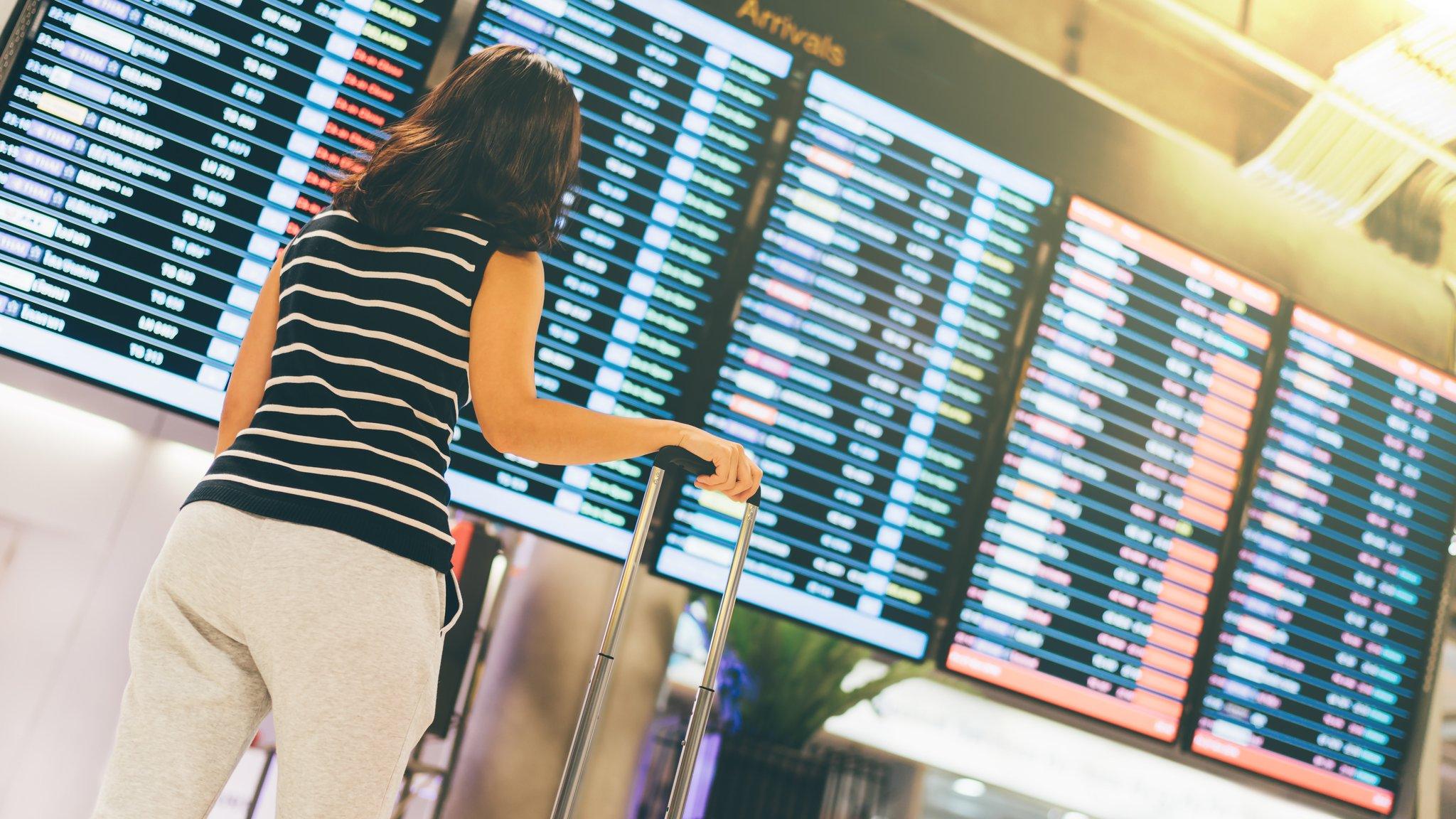 Woman standing in front of departure board