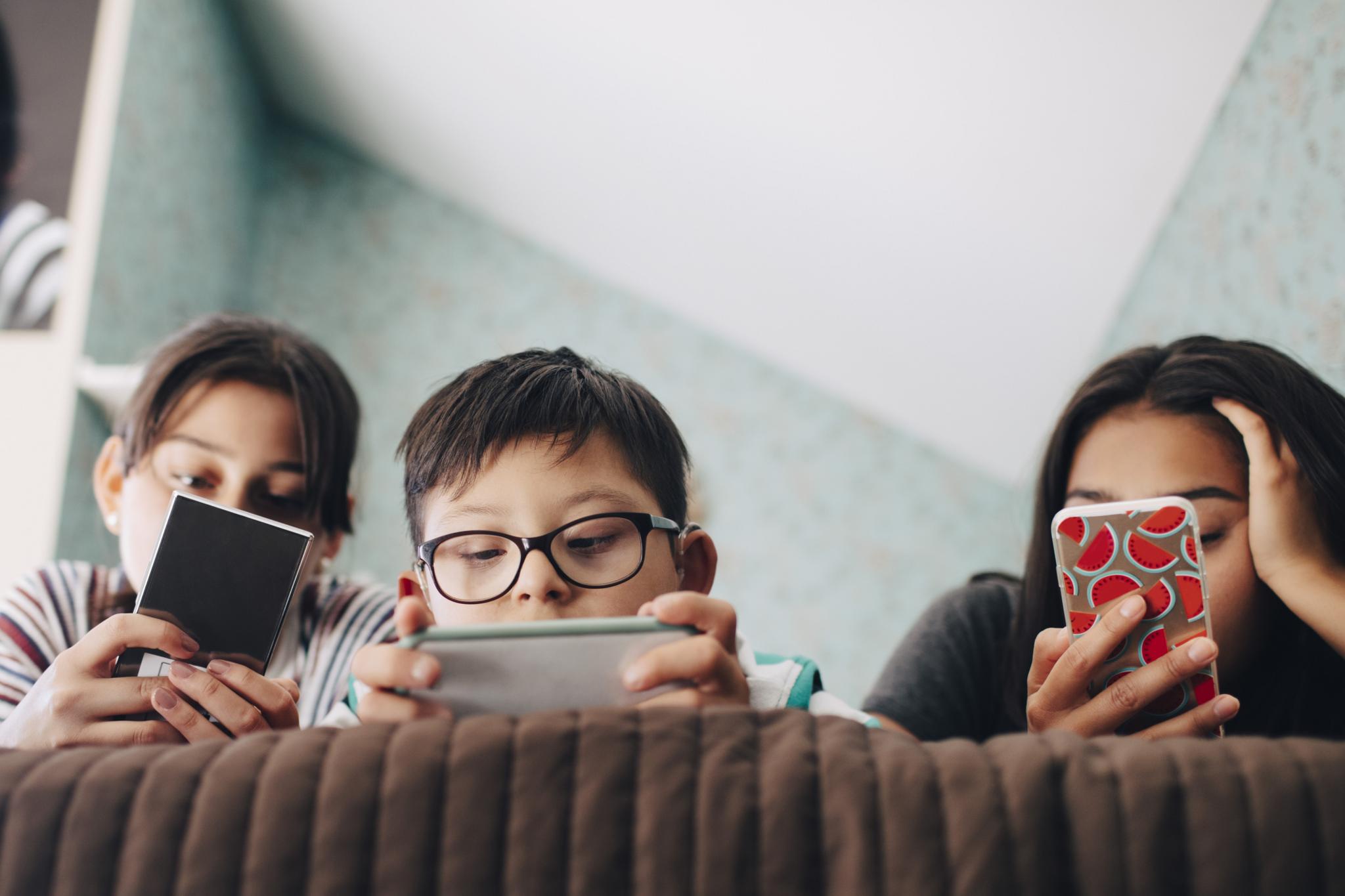 Three children on the sofa playing on their phone