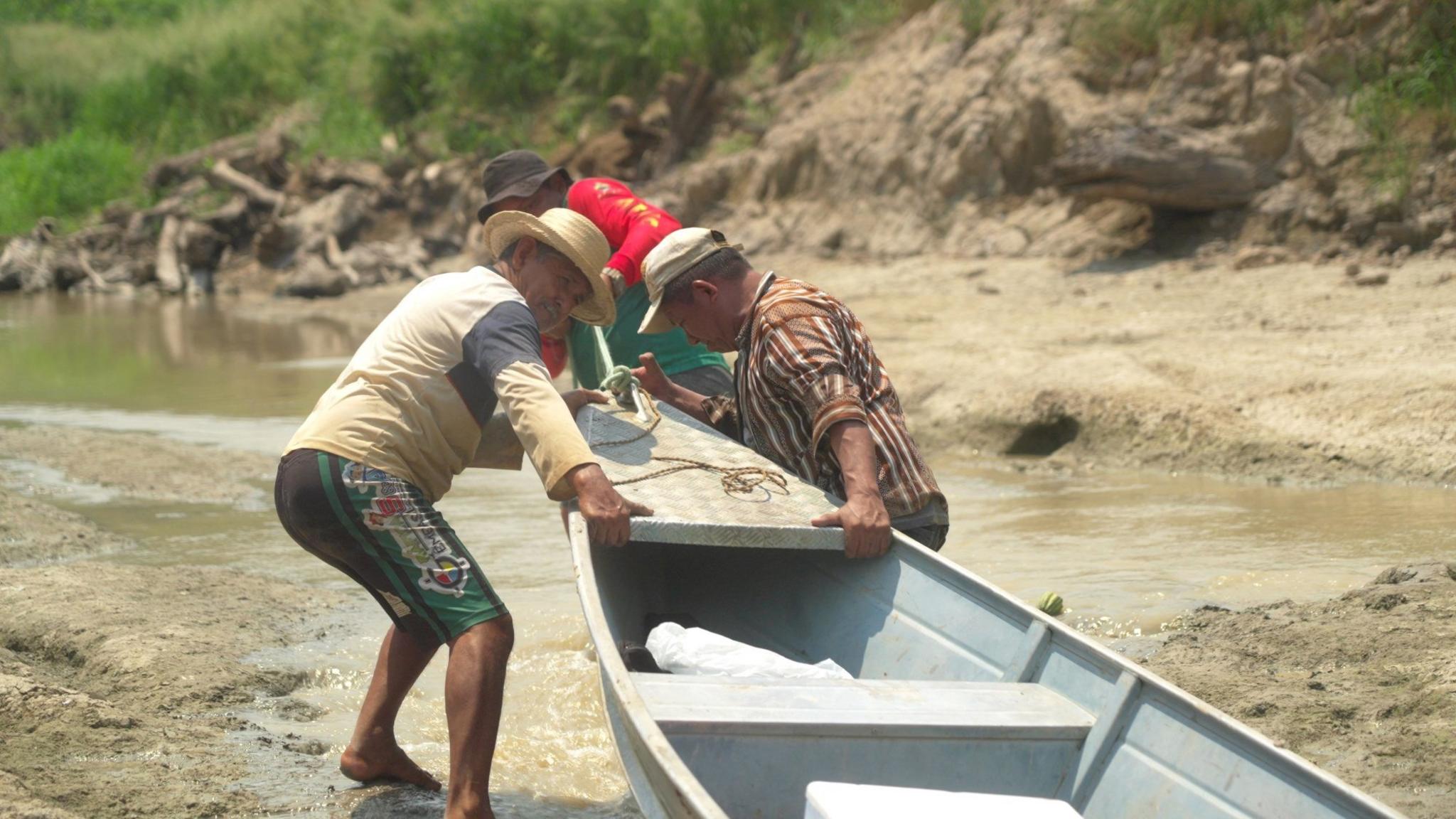 Oliveira and friends tugging his canoe along the dried-out creek