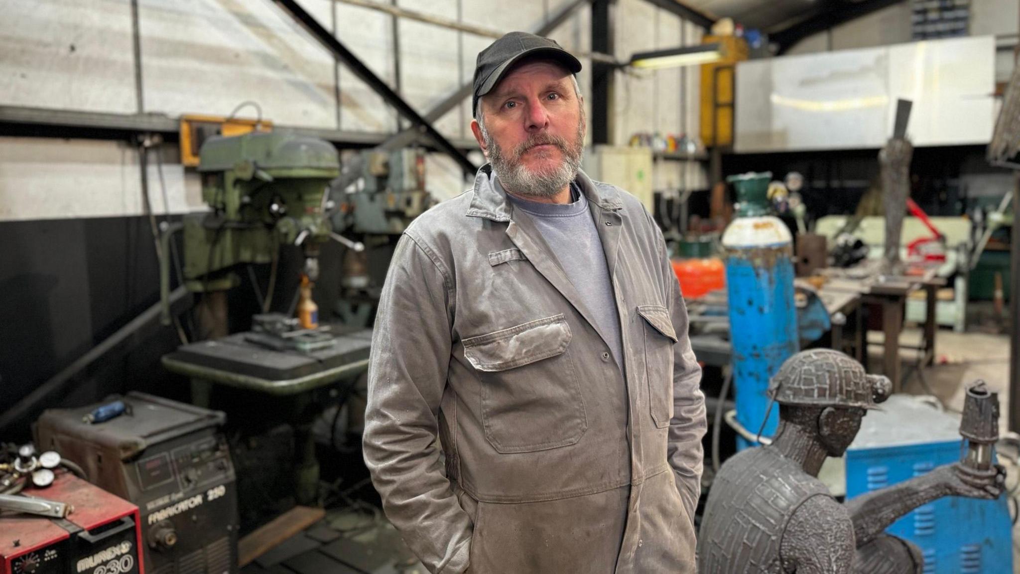 Ray Lonsdale in his workshop, surrounded by equipment and sculptures