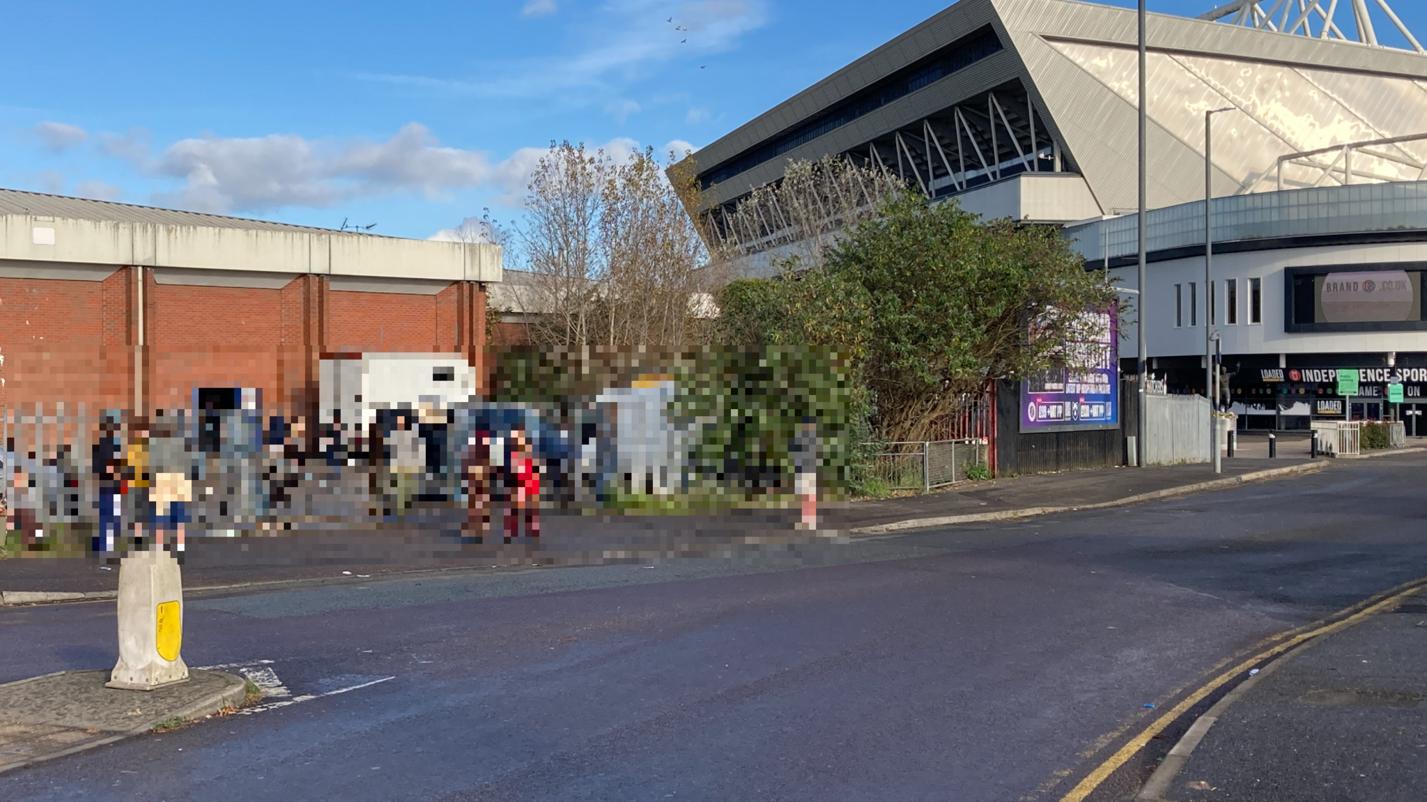 The view from outside the building with Ashton Gate Stadium in the distance. Some people stand outside, they have been pixelated.