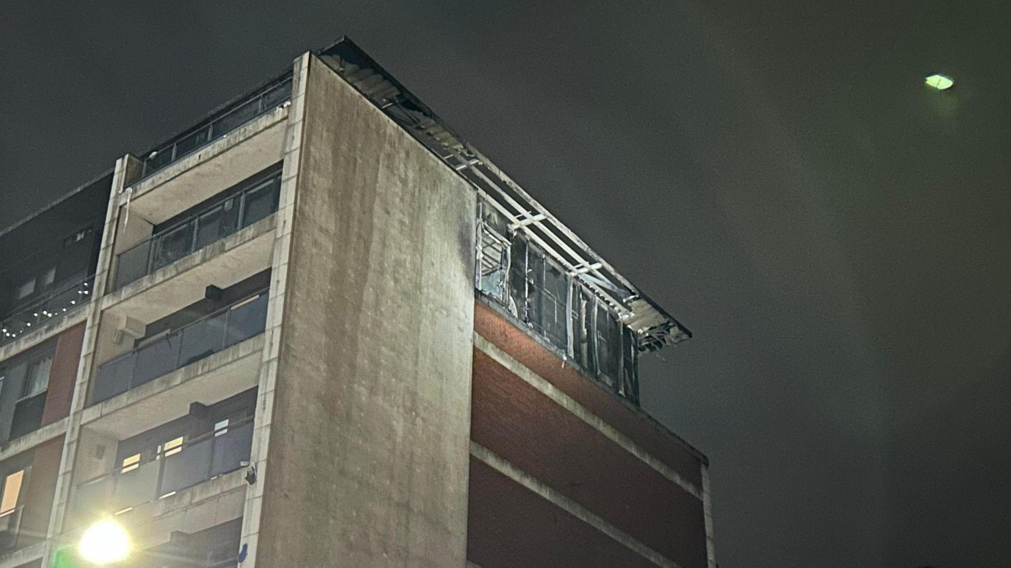 The side of the fire damaged building at the top of the building taken on Thursday morning - with a dark sky in the background 