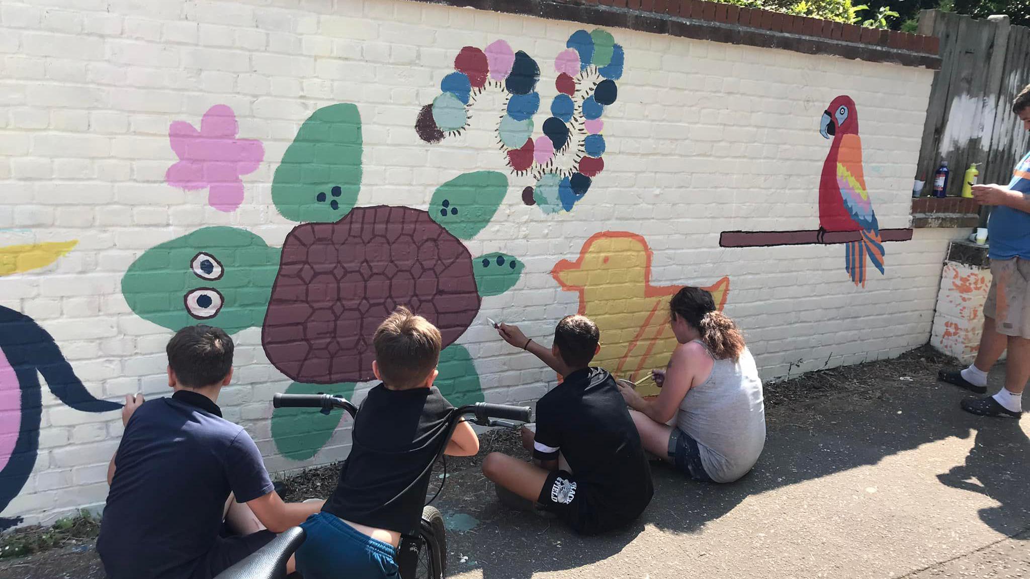 Children painting a mural on a wall