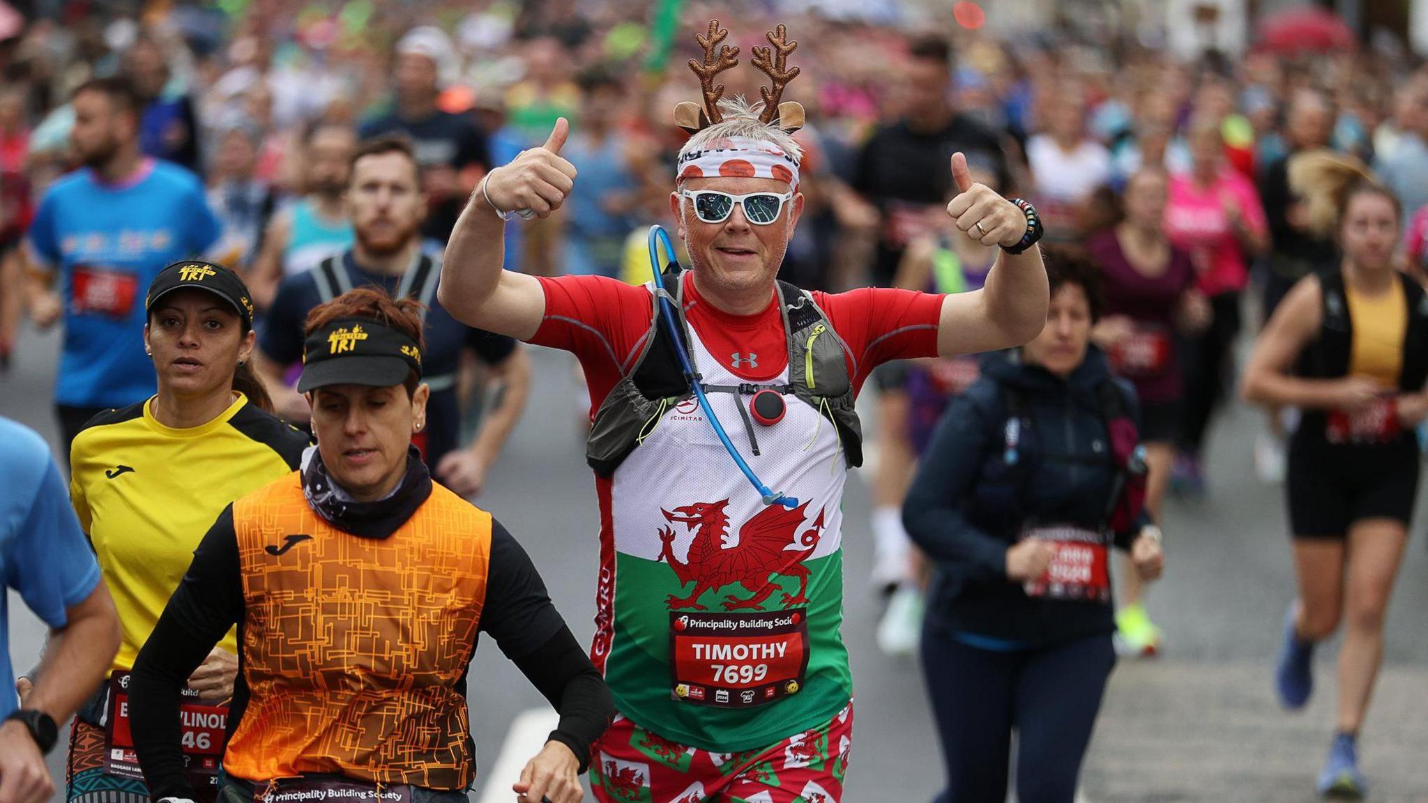 Runner wearing sunglasses, toy reindeer ears and a Welsh dragon on his tee-shirt is seen among the competitors