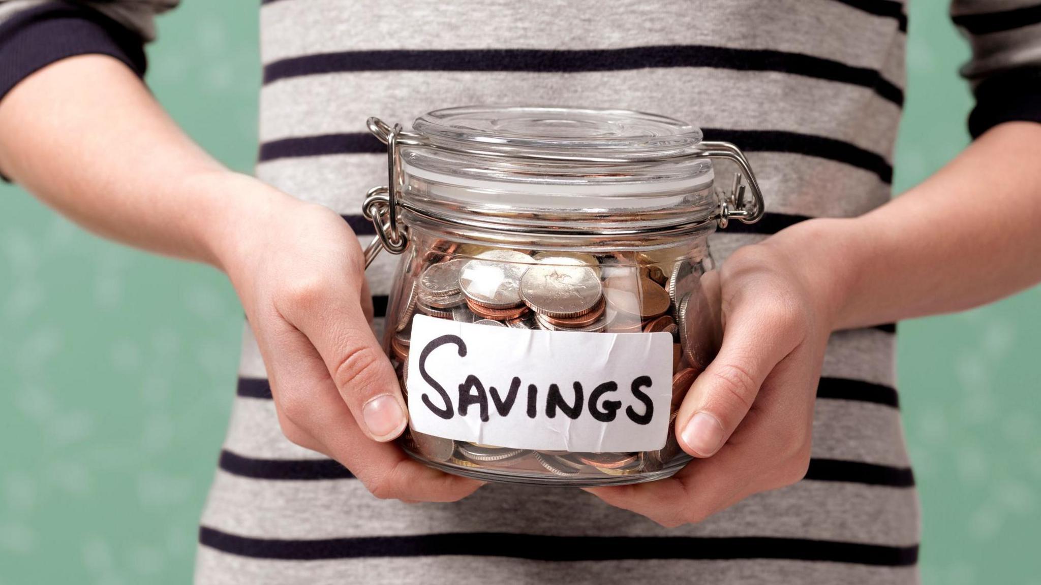 a child holding a jar of coins which says: savings on it