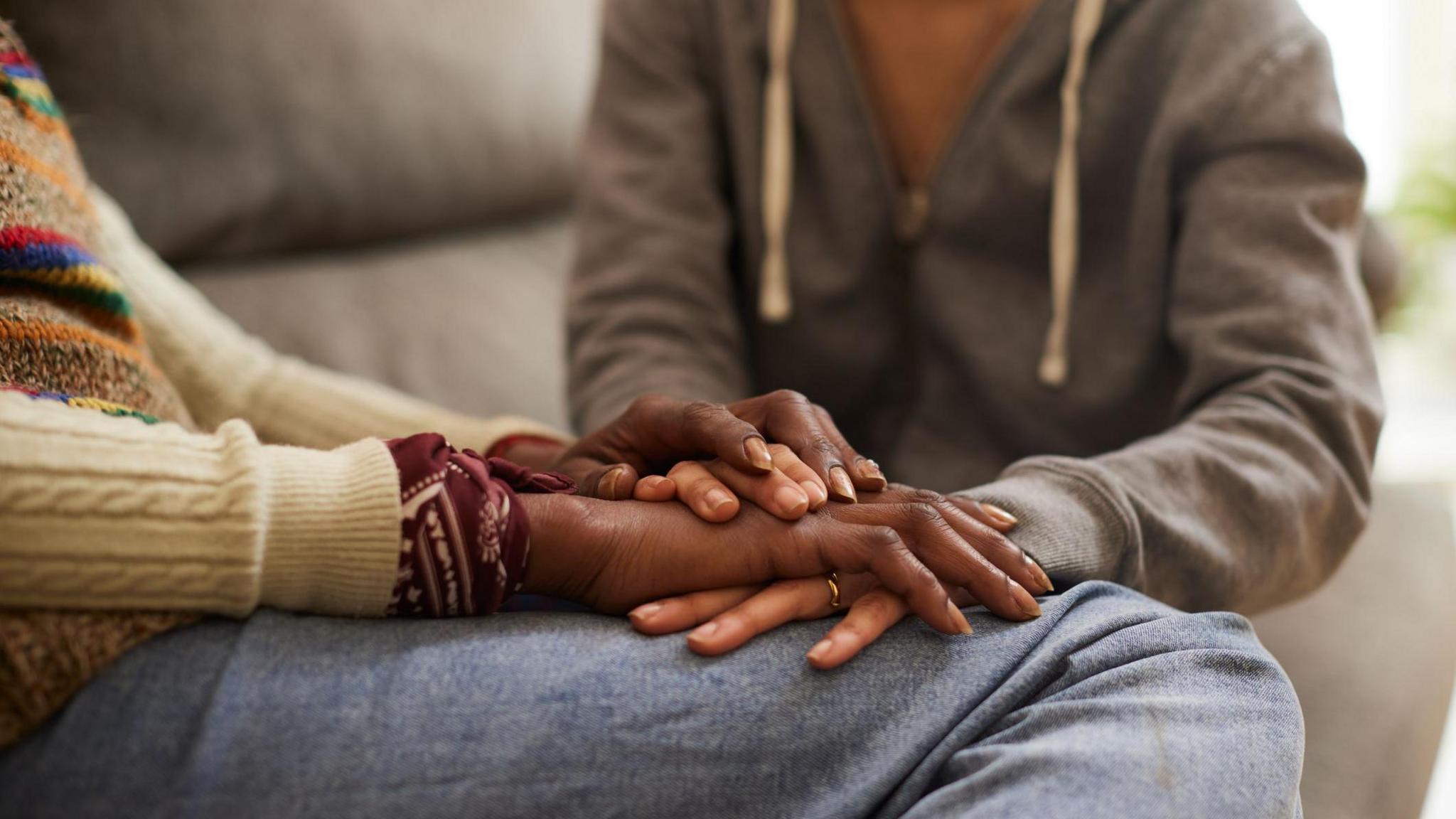 A close up image of a woman and her child holding hands