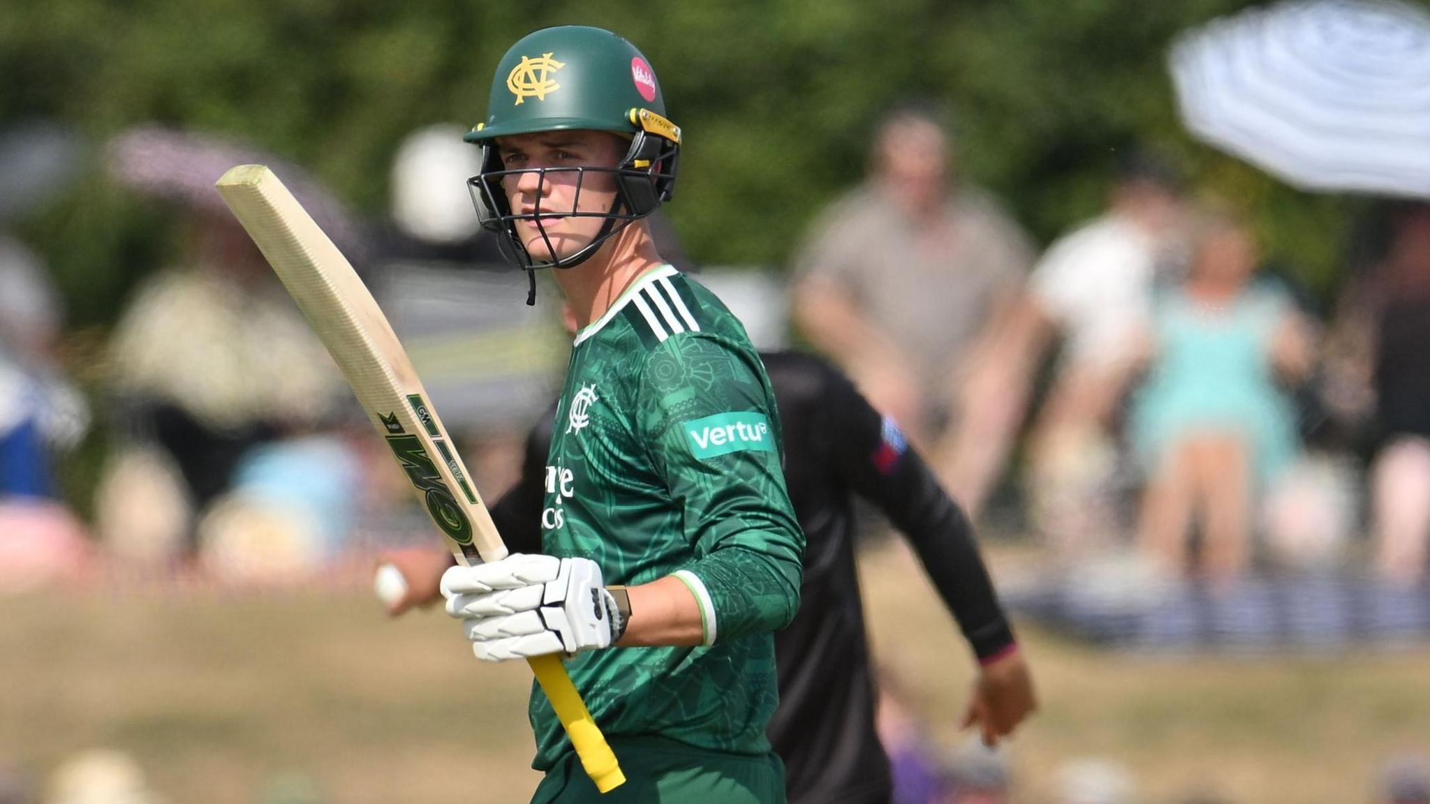 Freddie McCann raises his bat after scoring a half-century for Nottinghamshire