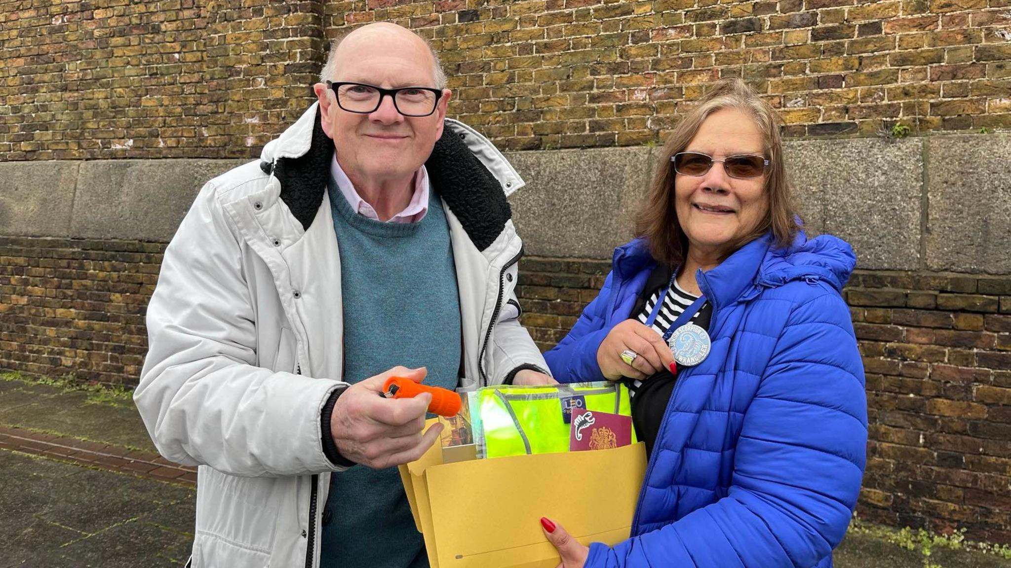 John Nurden and Jenny Hurkett with a club membership pack next to Sheerness Dock wall at Blue Town. They pair are both looking directly at the camera. 