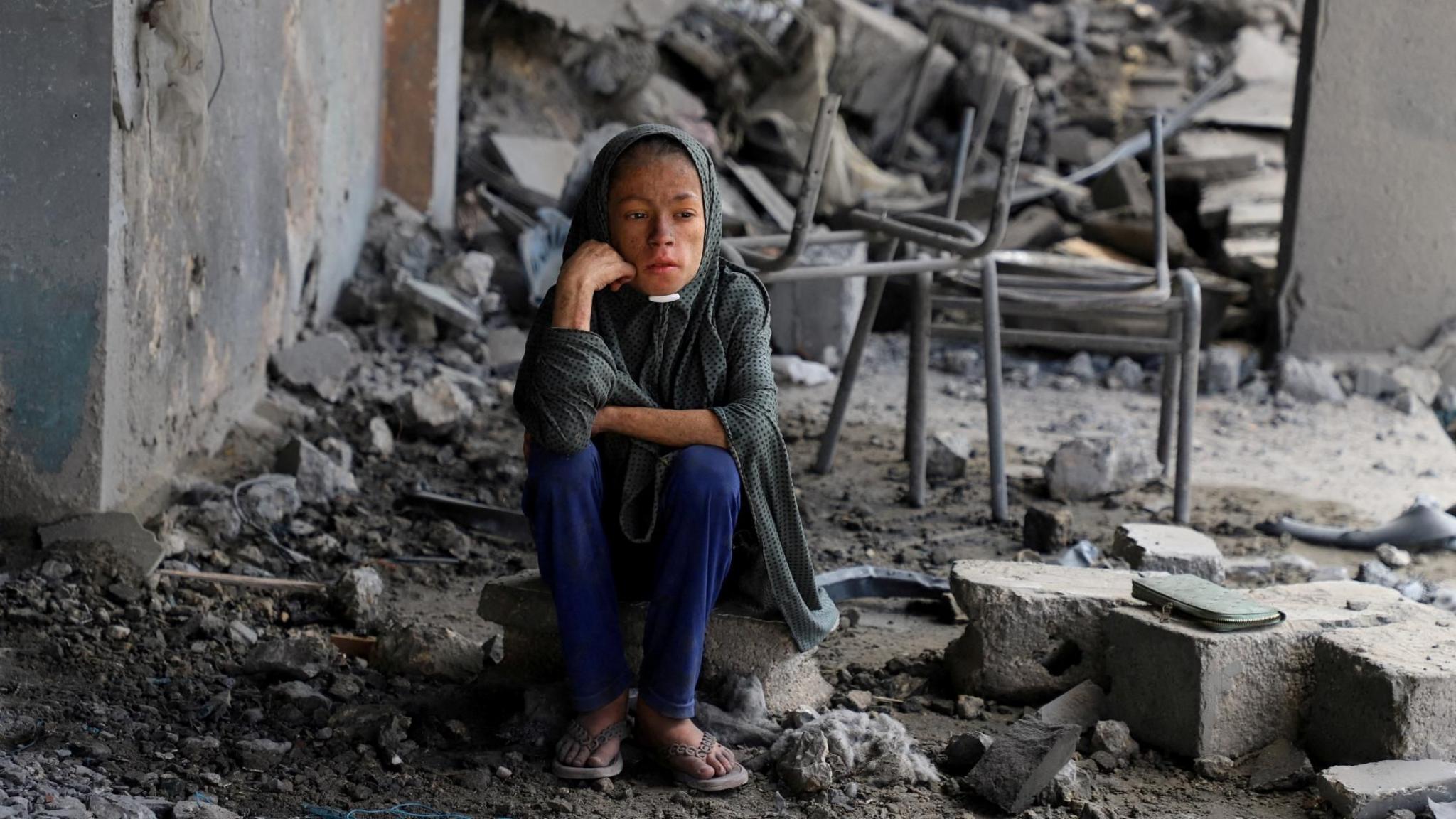 A Palestinian girl sits amid debris at a school in Gaza City's Zeitoun neighbourhood, where displaced people were taking shelter, after it was hit in an overnight Israeli strike (1 October 2025)