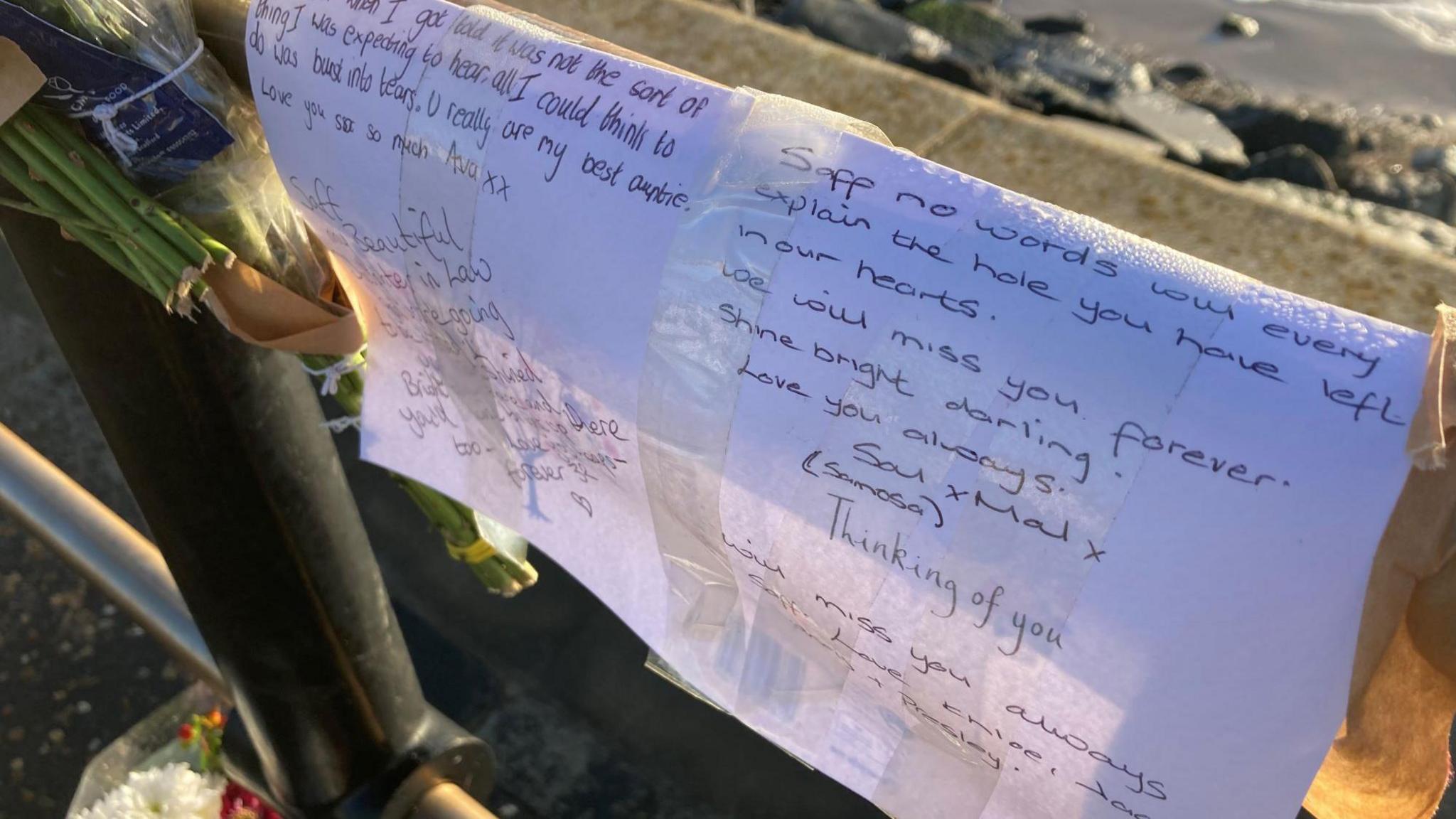 Double A4 sized papers with messages of love posted on a seawall barrier. 