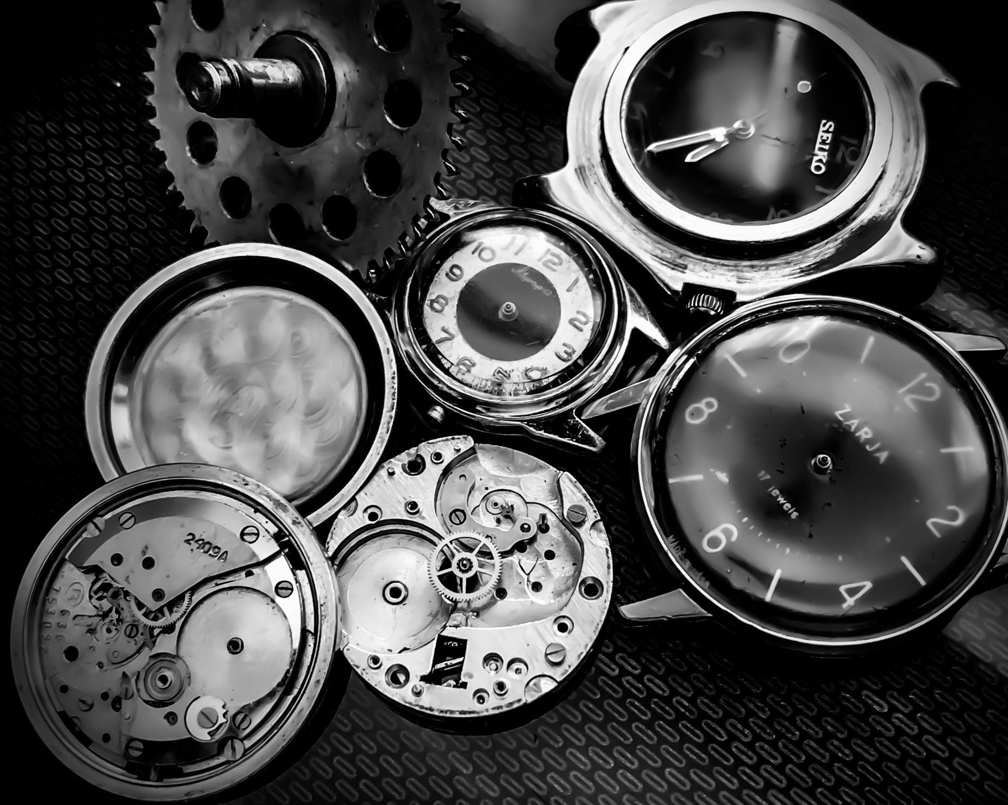 A collection of old watches - some taken apart to expose the insides of them.