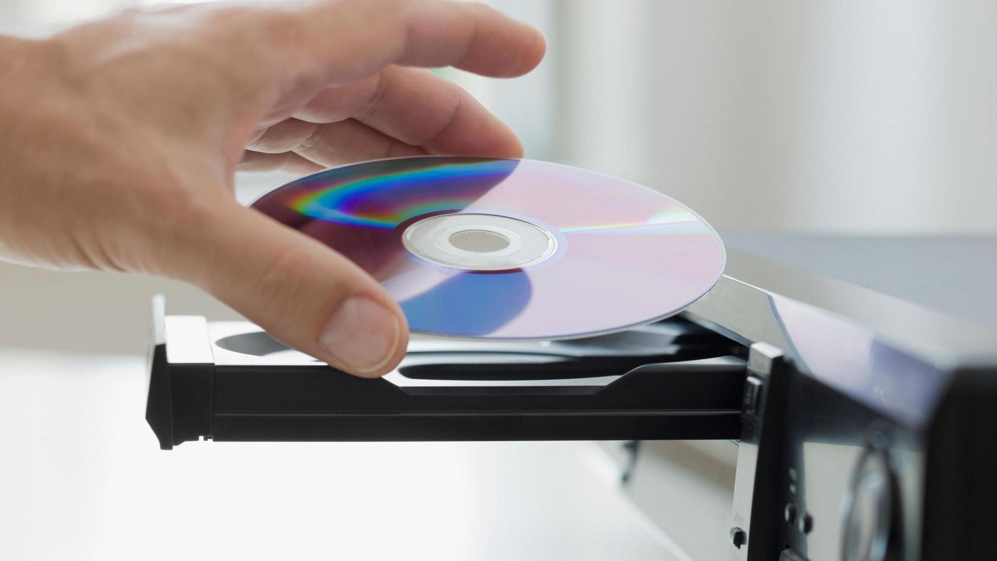 A man places a DVD disk into a DVD player