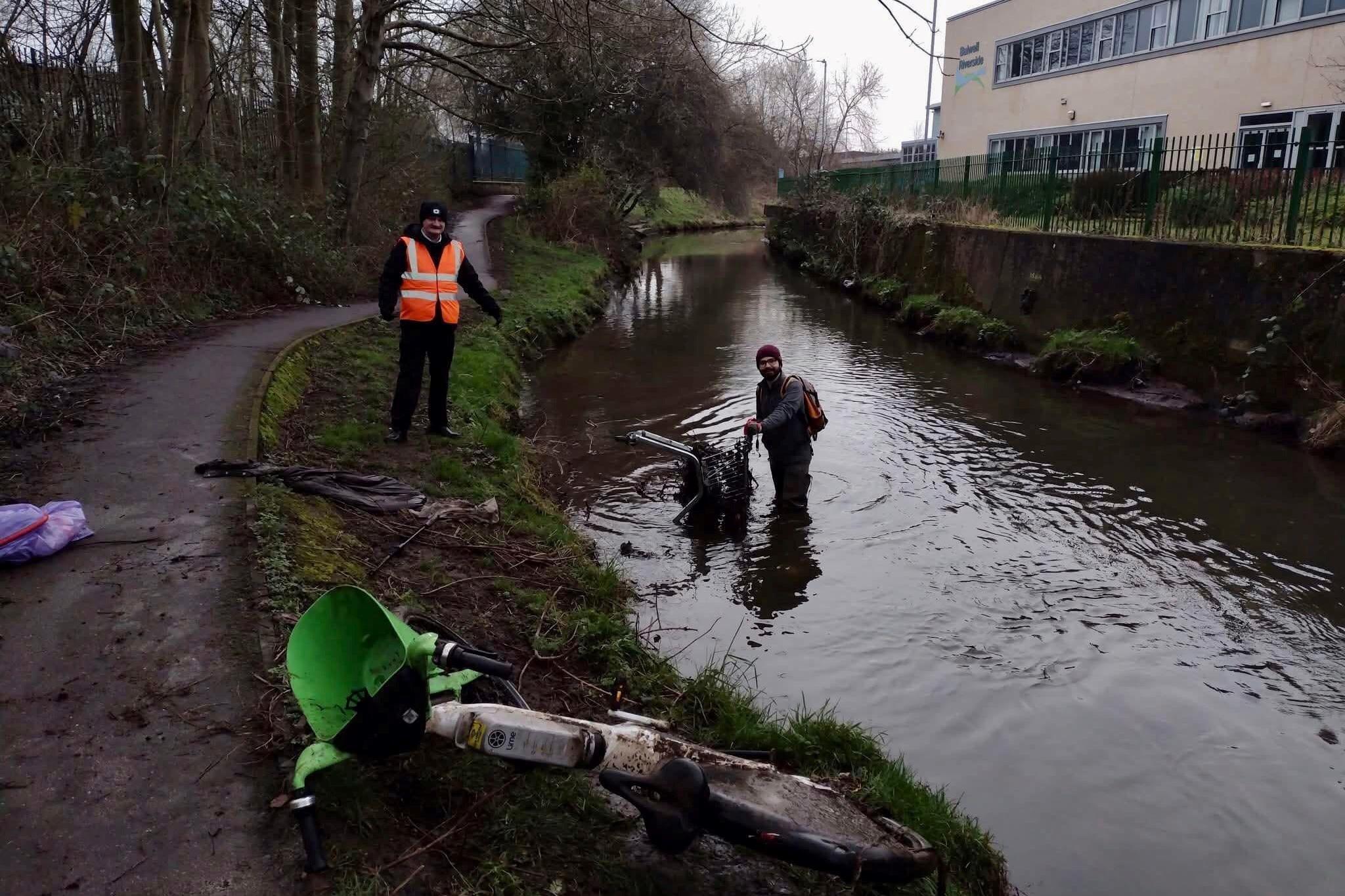 Ethan Radford standing in the River Leen with a Lime bike in the foreground